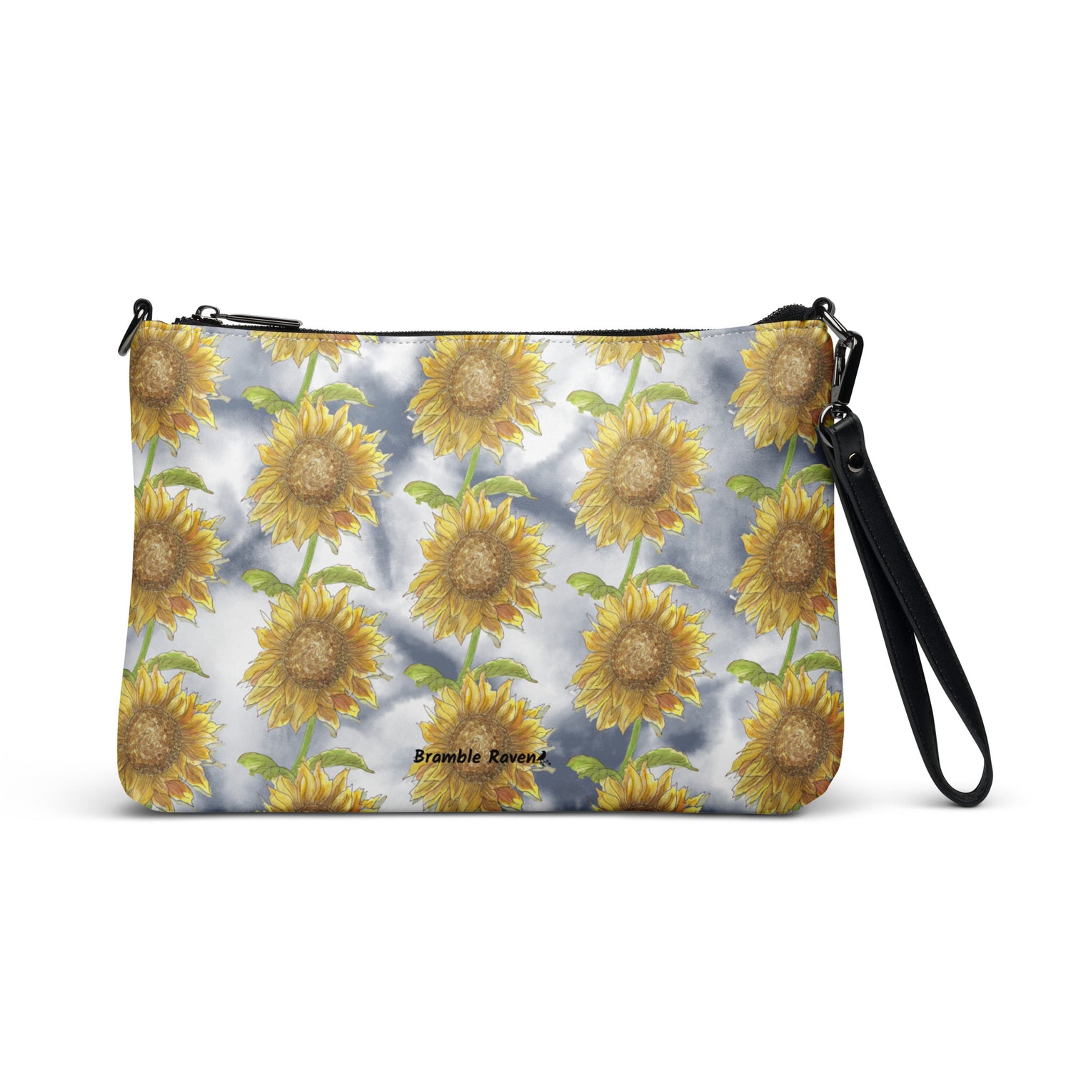 Sunflower crossbody bag. Faux leather with polyester lining and dark grey hardware. Comes with adjustable removable wrist and shoulder straps. Features patterned design of watercolor sunflowers against a cloudy background.