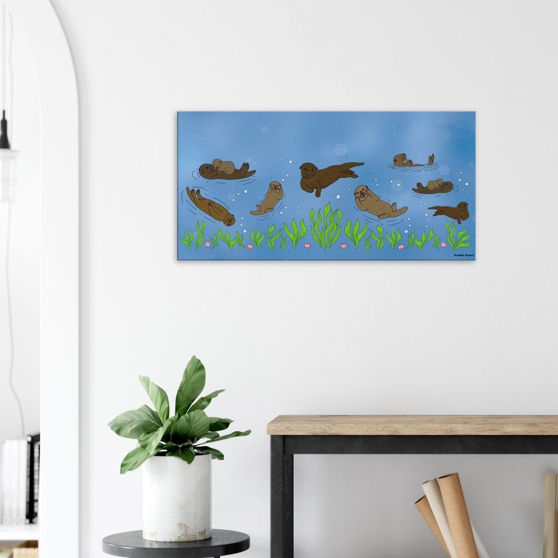 20 by 40 inch slim canvas wall art print of sea otters swimming along the seabed. Shown on wall above wooden end table and potted plant.