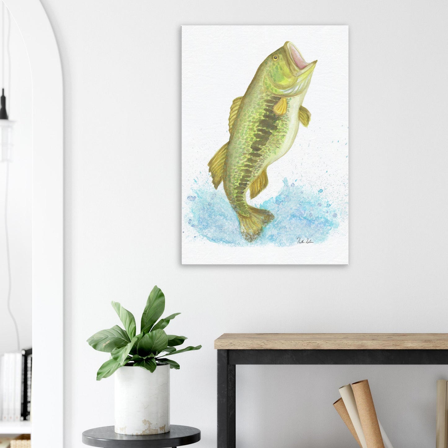 28 by 40 inch slim canvas wall art print featuring a watercolor painting of a largemouth bass leaping from the water. Shown on wall above wooden end table and potted plant.