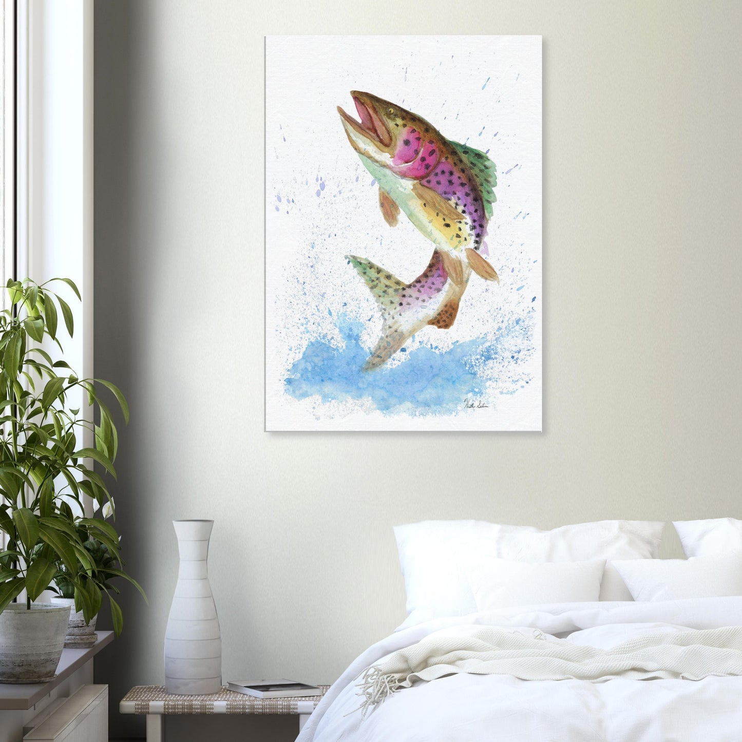 28 by 40 inch slim canvas wall art print featuring a watercolor painting of a rainbow trout leaping from the water. Shown on wall above white bed, end table, and potted plant.