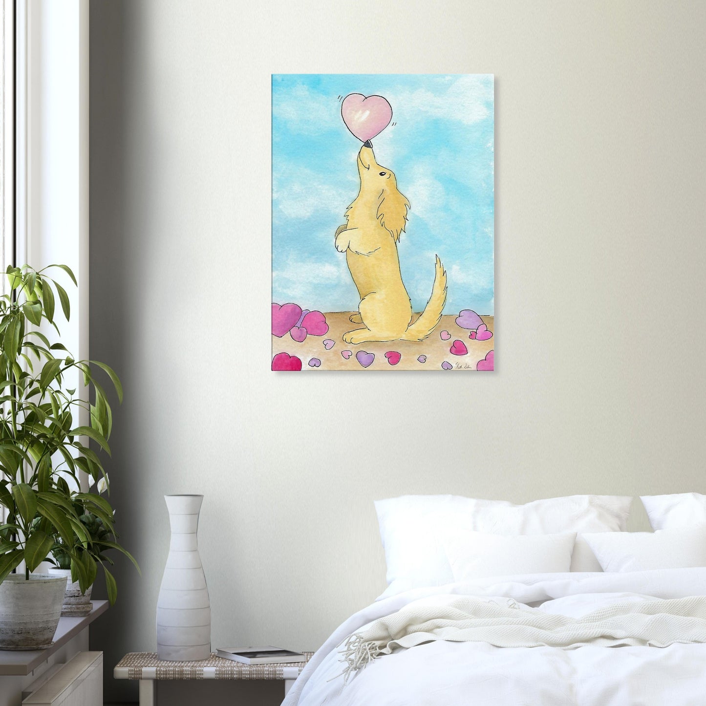 24 by 32 inch canvas wall art print of Heather Silver's watercolor painting, Puppy Love. It features a cute dog balancing a pink heart on its nose against a blue sky background. Canvas shown on wall above white bed with nightstand and potted plant.