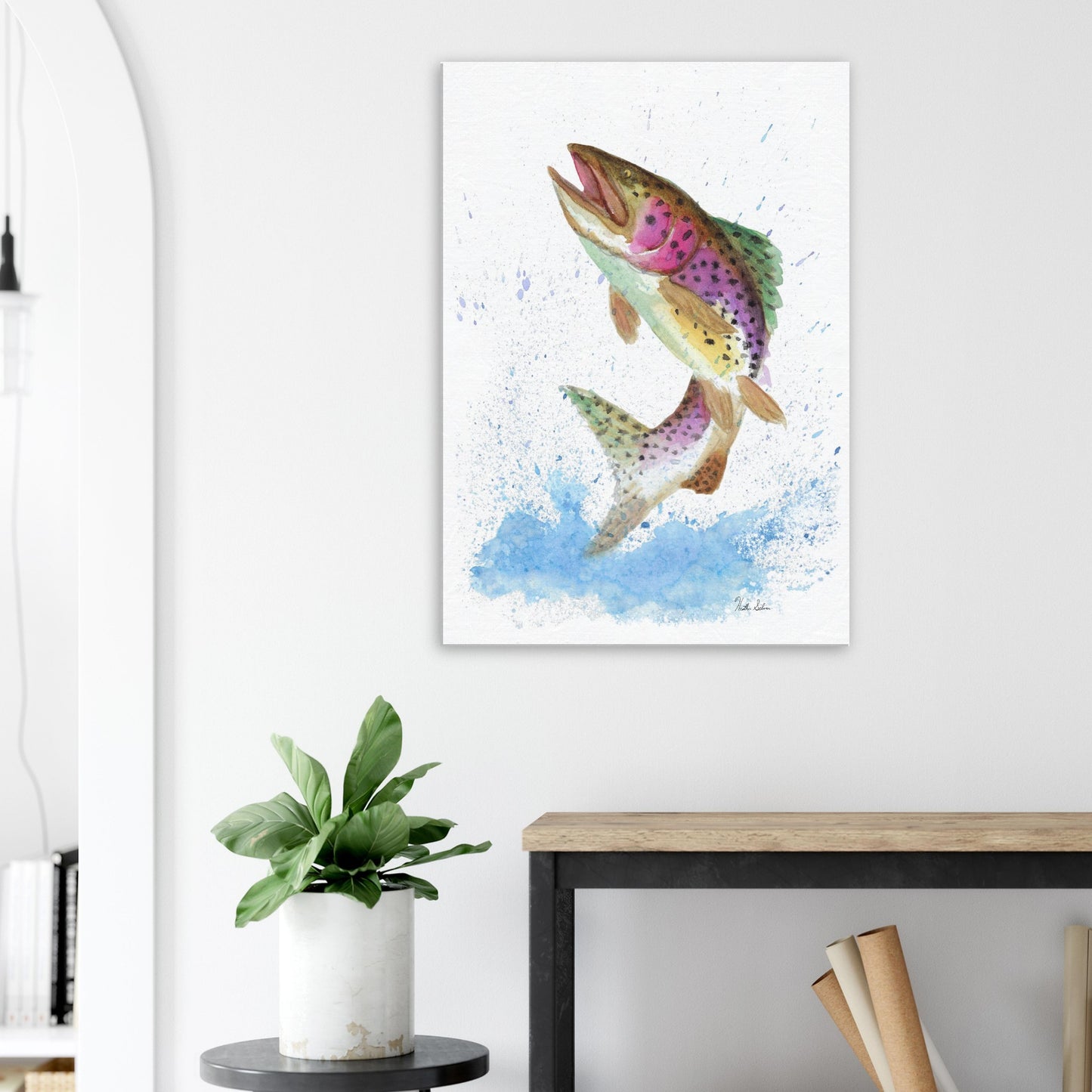 28 by 40 inch slim canvas wall art print featuring a watercolor painting of a rainbow trout leaping from the water. Shown on wall above wooden end table and potted plant.