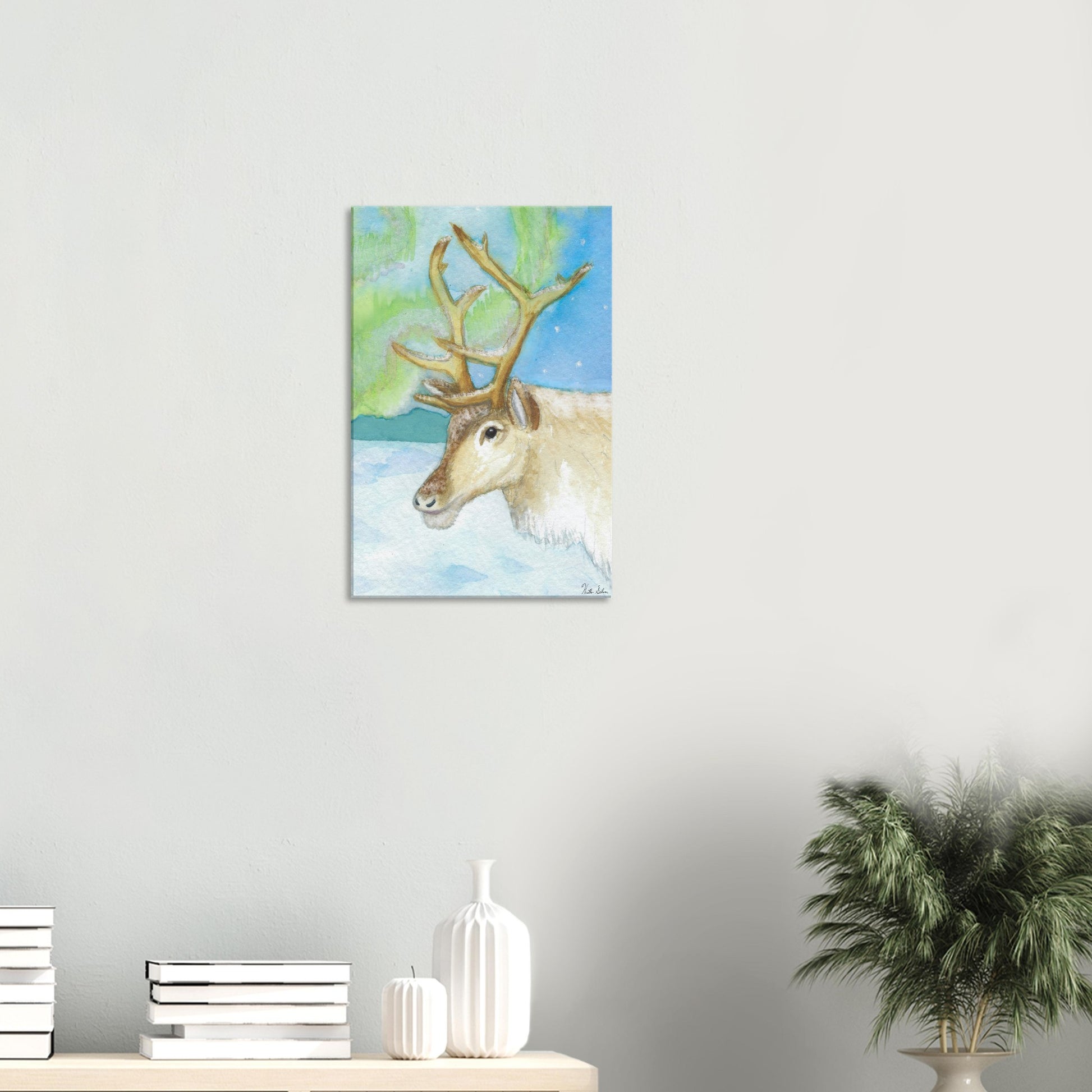 16 by 24 inch slim canvas print of Heather Silver's watercolor painting, northern lights reindeer. Shown on wall above dresser with books and potted plant.