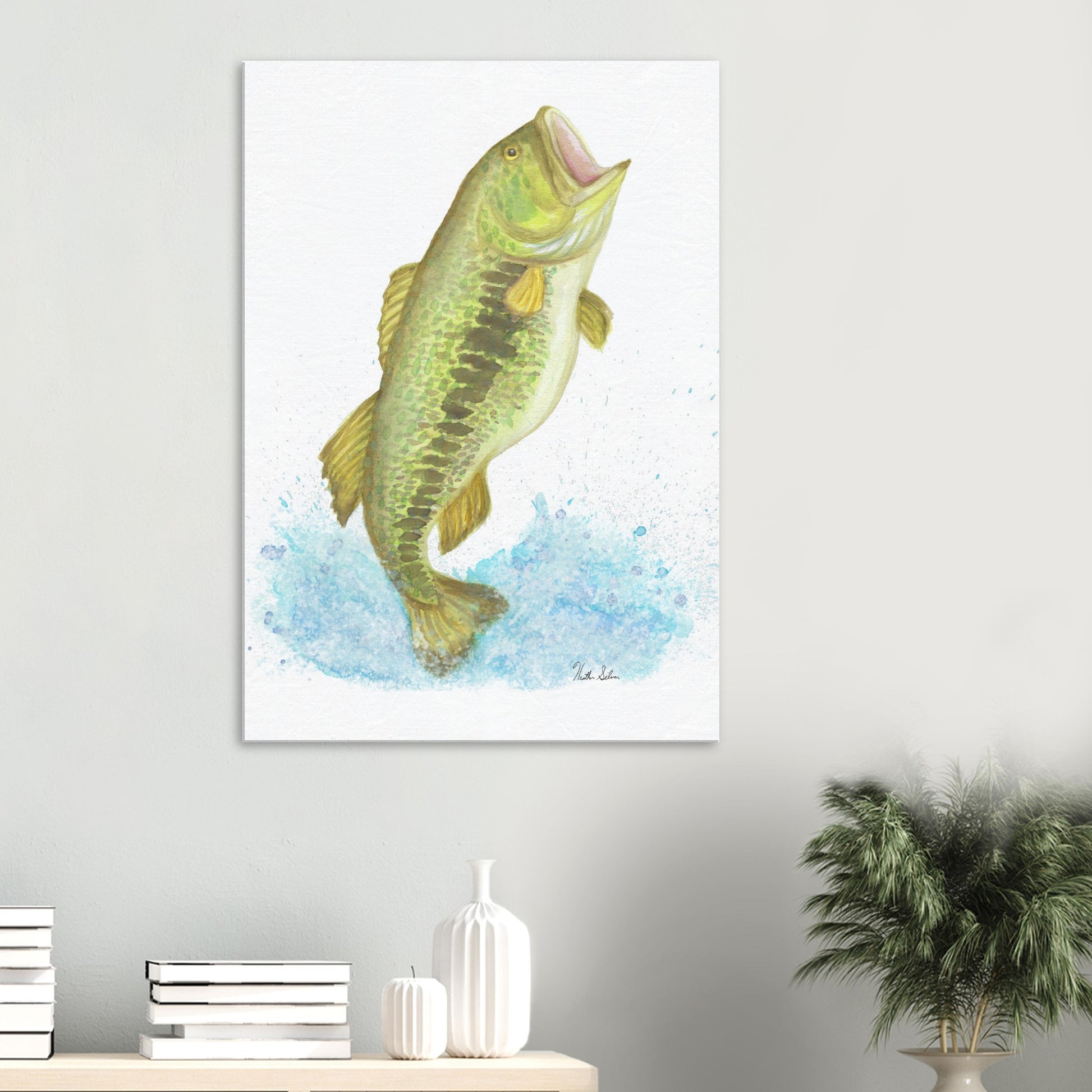 28 by 40 inch slim canvas wall art print featuring a watercolor painting of a largemouth bass leaping from the water. Shown above desktop with books and potted plant.