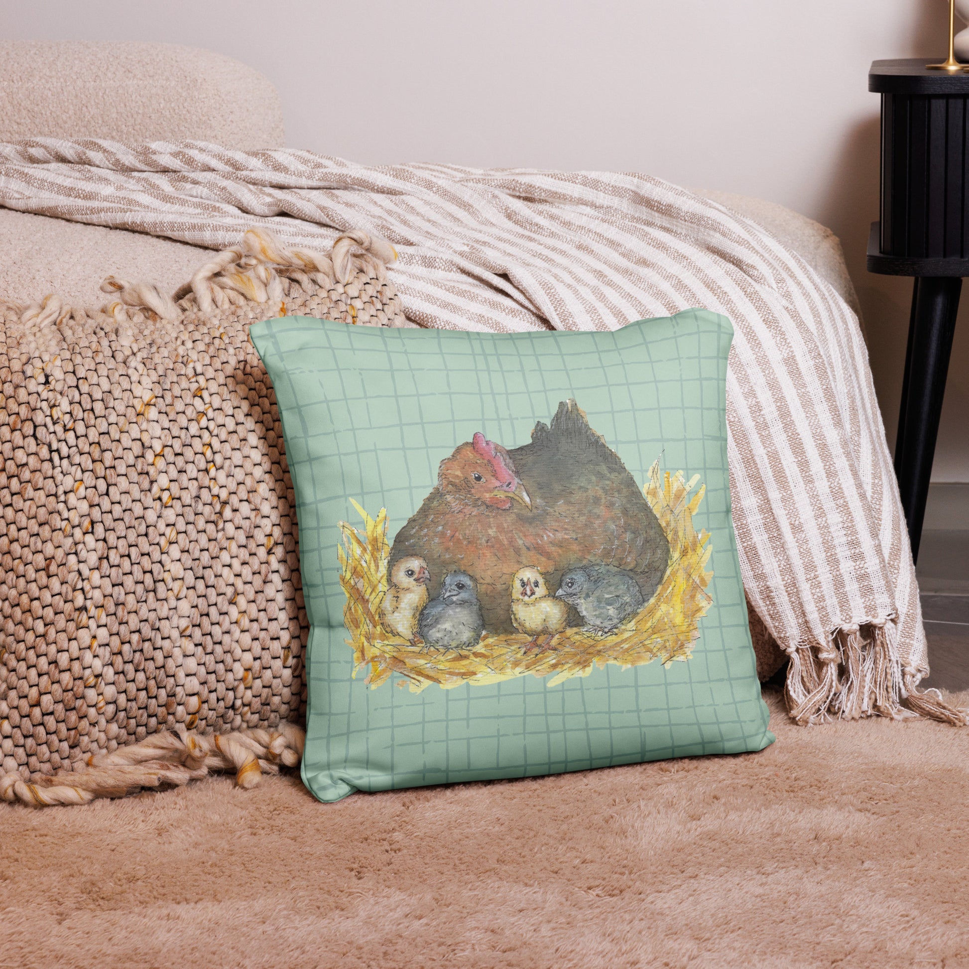 18 by 18 inch mother hen decorative throw pillow. Features Heather Silver's watercolor print of a mother hen and chicks on a green cross-hatched background. Image printed on both sides. Has a hidden zipper and washable cover. Comes with shape-retaining insert. Back view of pillow on tan carpet.