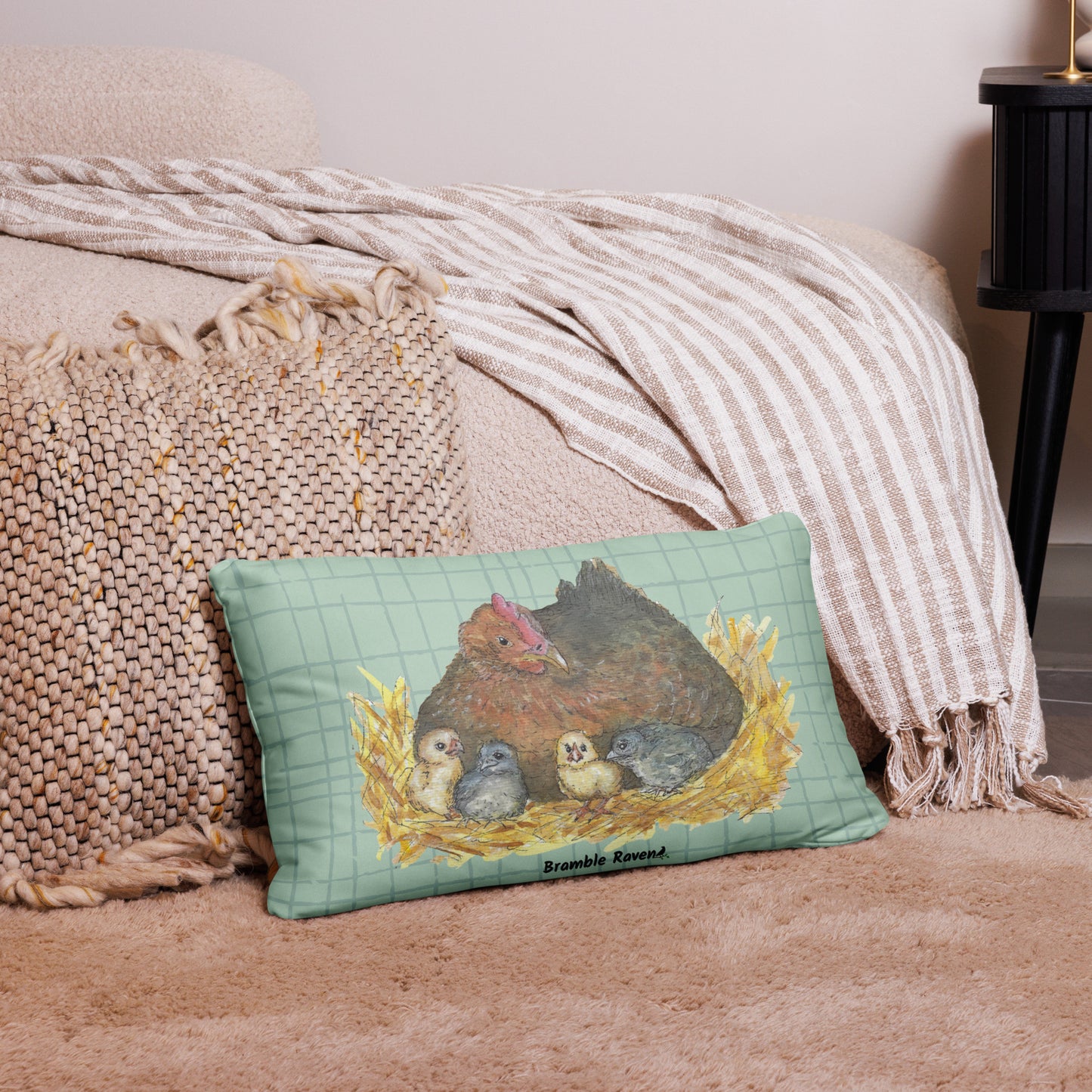20 by 12 inch mother hen decorative throw pillow. Features Heather Silver's watercolor print of a mother hen and chicks on a green cross-hatched background. Image printed on both sides. Has a hidden zipper and washable cover. Comes with shape-retaining insert. Shown on tan carpet by beige bed.