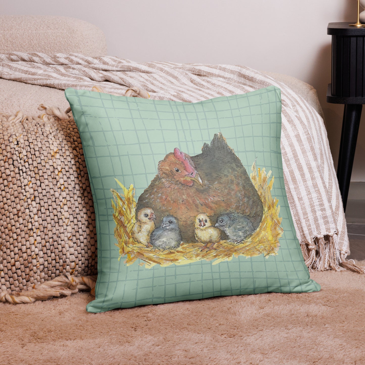 22 by 22 inch mother hen decorative throw pillow. Features Heather Silver's watercolor print of a mother hen and chicks on a green cross-hatched background. Image printed on both sides. Has a hidden zipper and washable cover. Comes with shape-retaining insert. Back view of pillow on tan carpet by beige bed.
