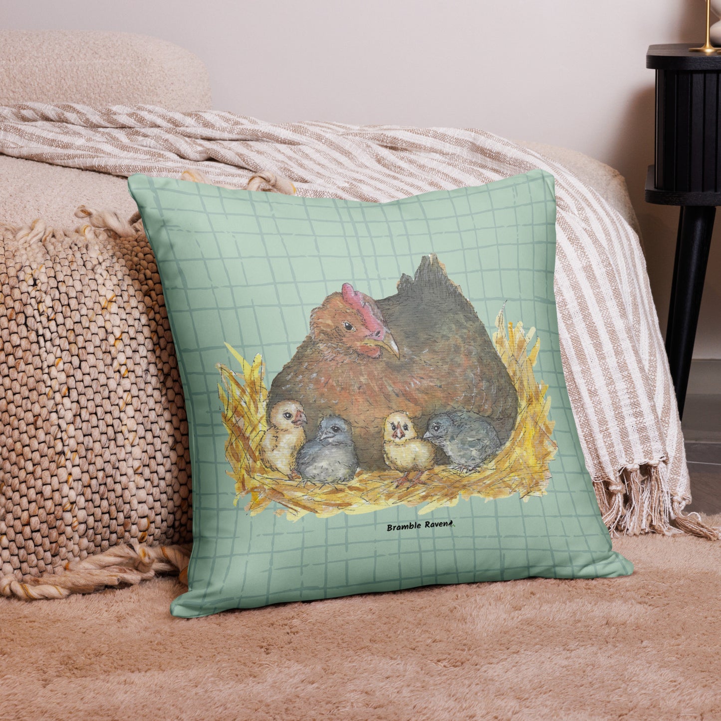 22 by 22 inch mother hen decorative throw pillow. Features Heather Silver's watercolor print of a mother hen and chicks on a green cross-hatched background. Image printed on both sides. Has a hidden zipper and washable cover. Comes with shape-retaining insert. Shown on tan carpet by beige bed.