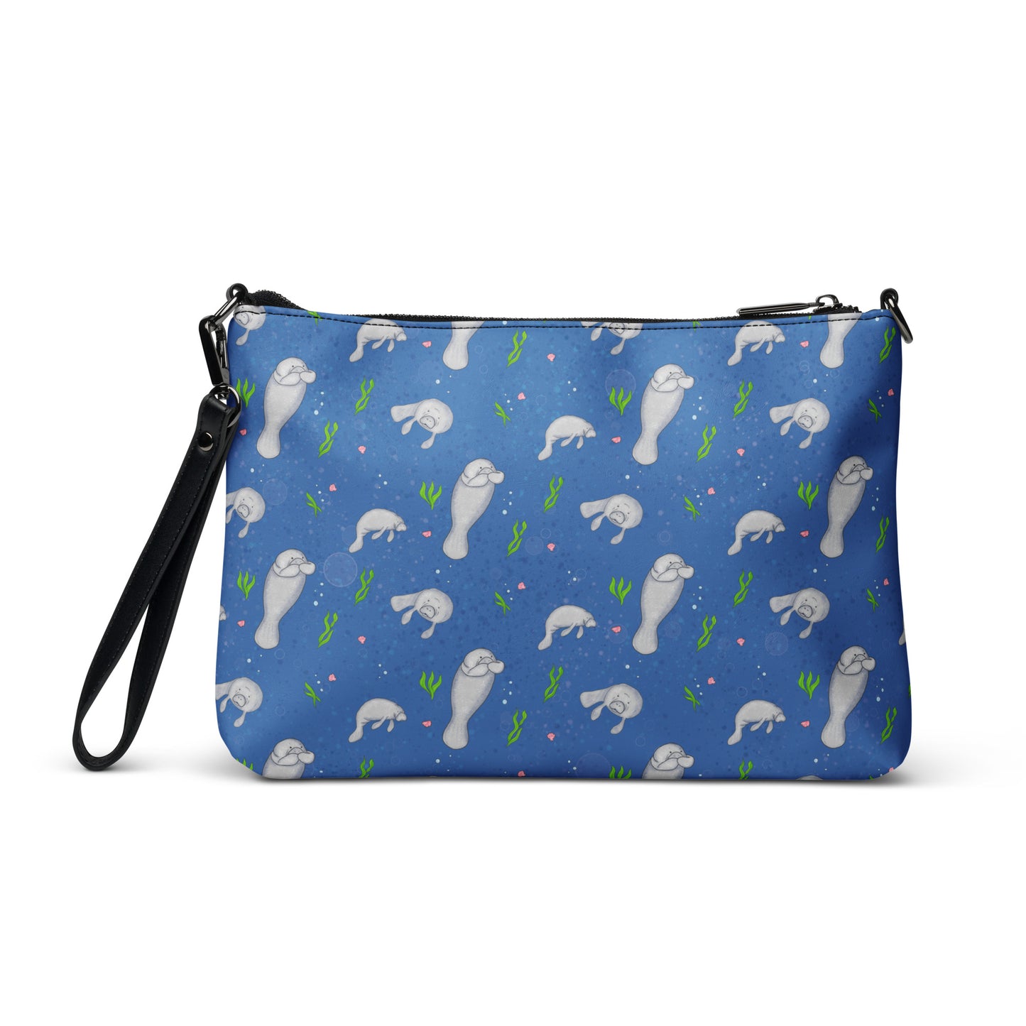 Manatee crossbody bag. Faux leather with polyester lining and dark grey hardware. Comes with adjustable removable wrist and shoulder straps. Back view of bag with manatees patterned on a dark blue background.
