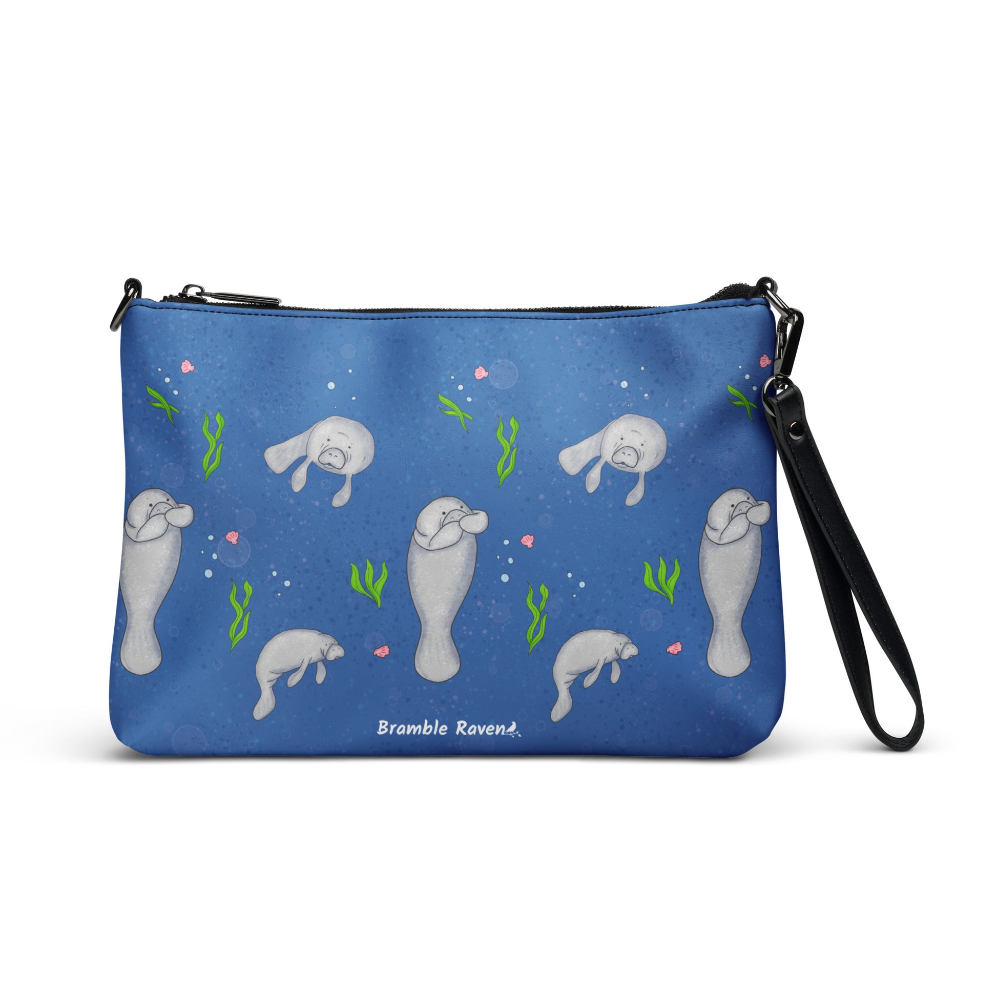 Manatee crossbody bag. Faux leather with polyester lining and dark grey hardware. Comes with adjustable removable wrist and shoulder straps. Front view of bag with manatees on a dark blue background.