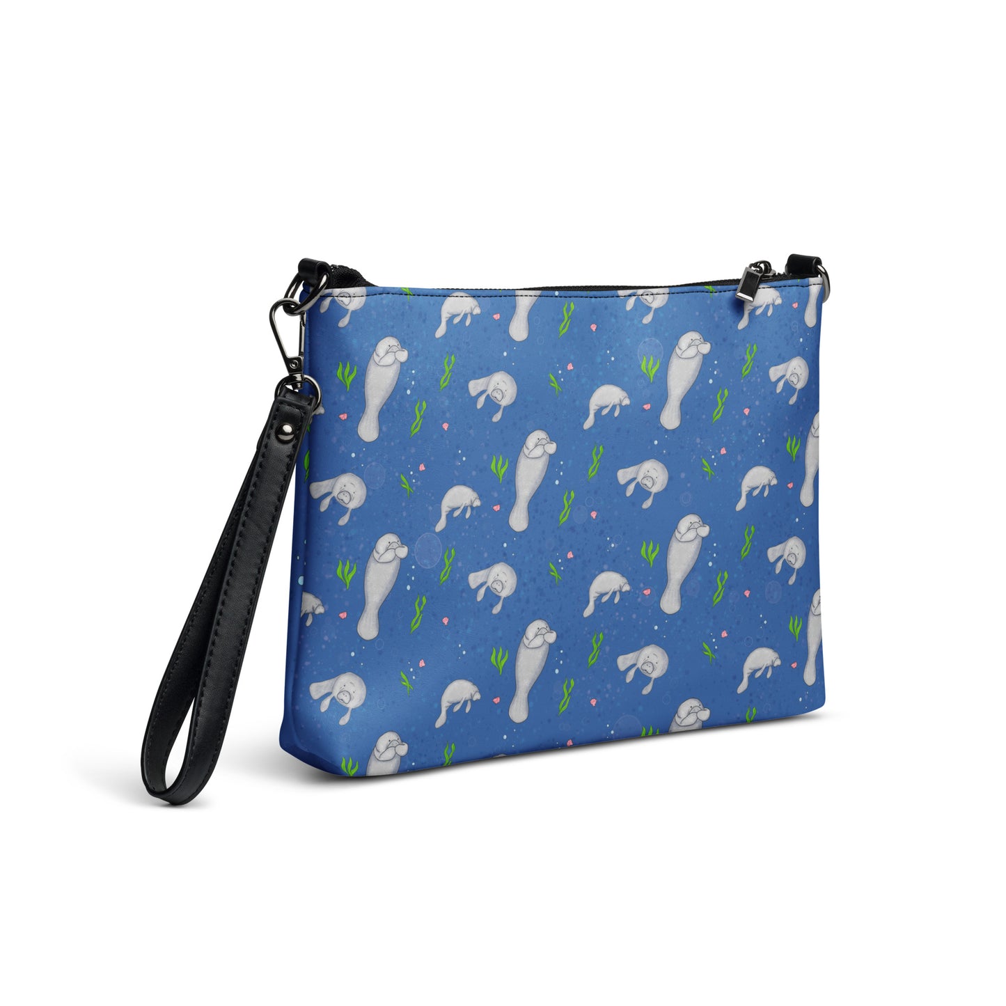 Manatee crossbody bag. Faux leather with polyester lining and dark grey hardware. Comes with adjustable removable wrist and shoulder straps. Back view of bag with manatees patterned on a dark blue background.