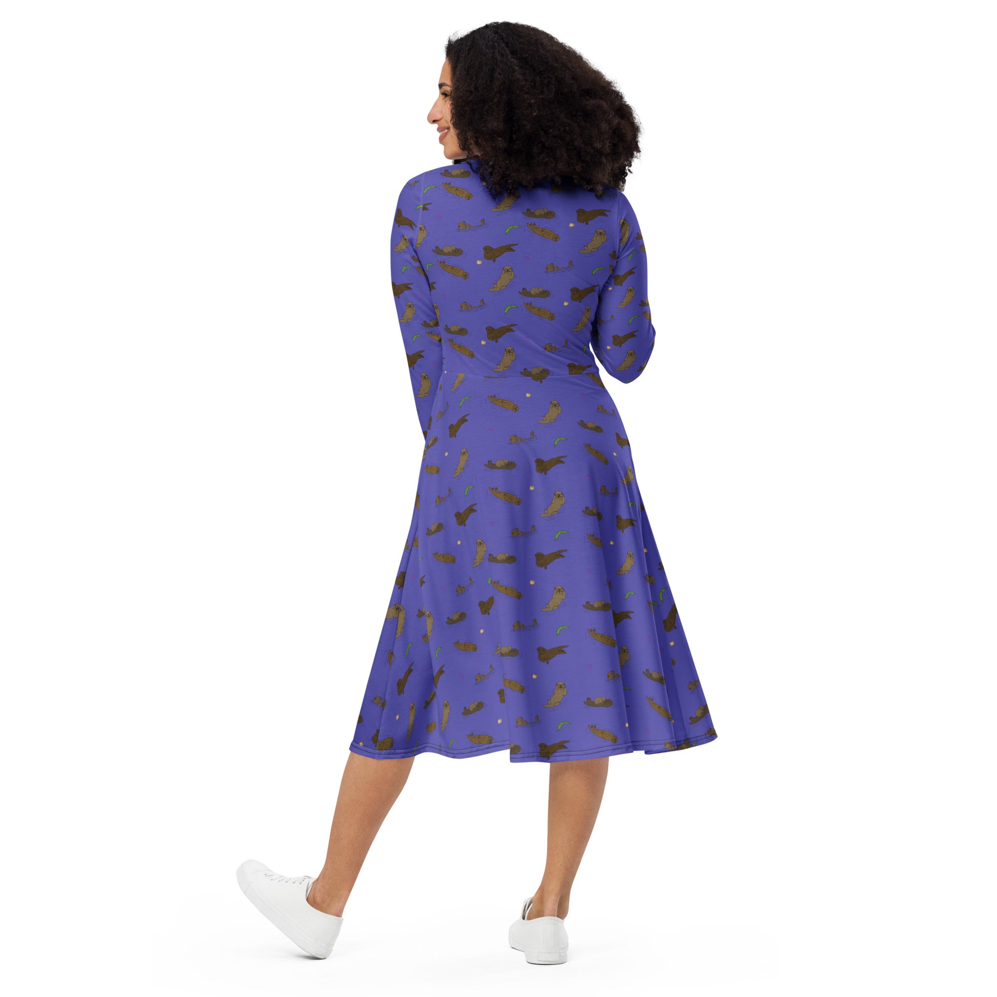 Long sleeve midi dress with fitted waist, flared bottom, and side pockets. Features a patterned design of sea otters, seashells, seaweed, and sea urchins on a purple background. Back view shown on female model.