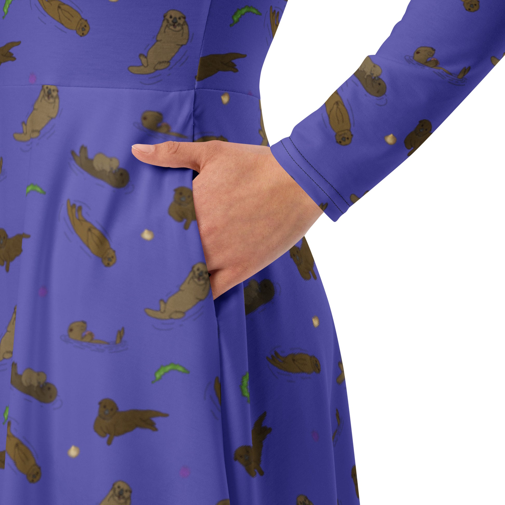 Long sleeve midi dress with fitted waist, flared bottom, and side pockets. Features a patterned design of sea otters, seashells, seaweed, and sea urchins on a purple background. Detail view of model's hand in pocket.