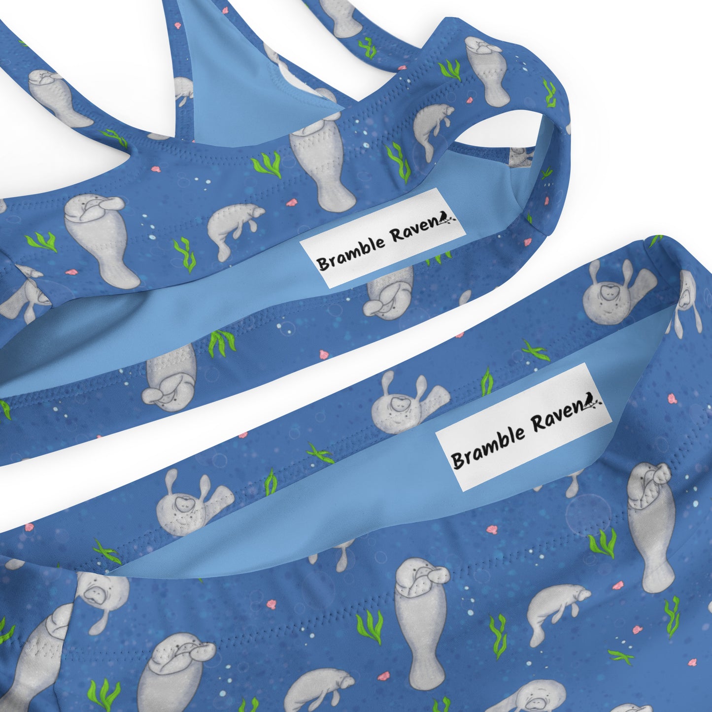 High-waisted bikini with hand-illustrated manatee pattern on a blue background. Made from recycled polyester combined with stretchable fabric. Has double layers and removable pads. Detail view of inner lining and zigzag stitching.