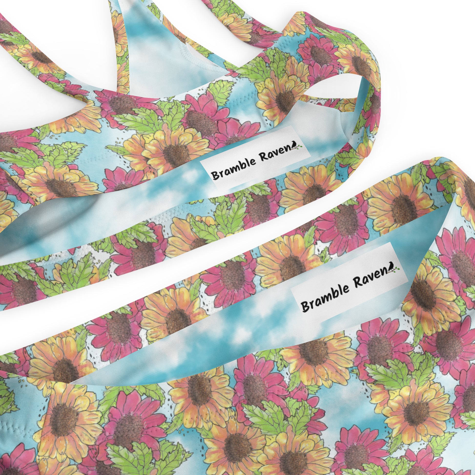 Watercolor Gerber daisy patterned high-waisted bikini. Made from recycled polyester and spandex. Features removable pads and double layers. Detail view of inside printed label.