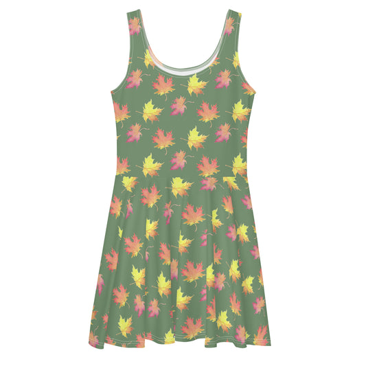 Sleeveless fall leaves skater dress. Has patterned print of watercolor fall leaves on a muted green background. Made from polyester and spandex. Has a mid-thigh length skirt and elastic waist.