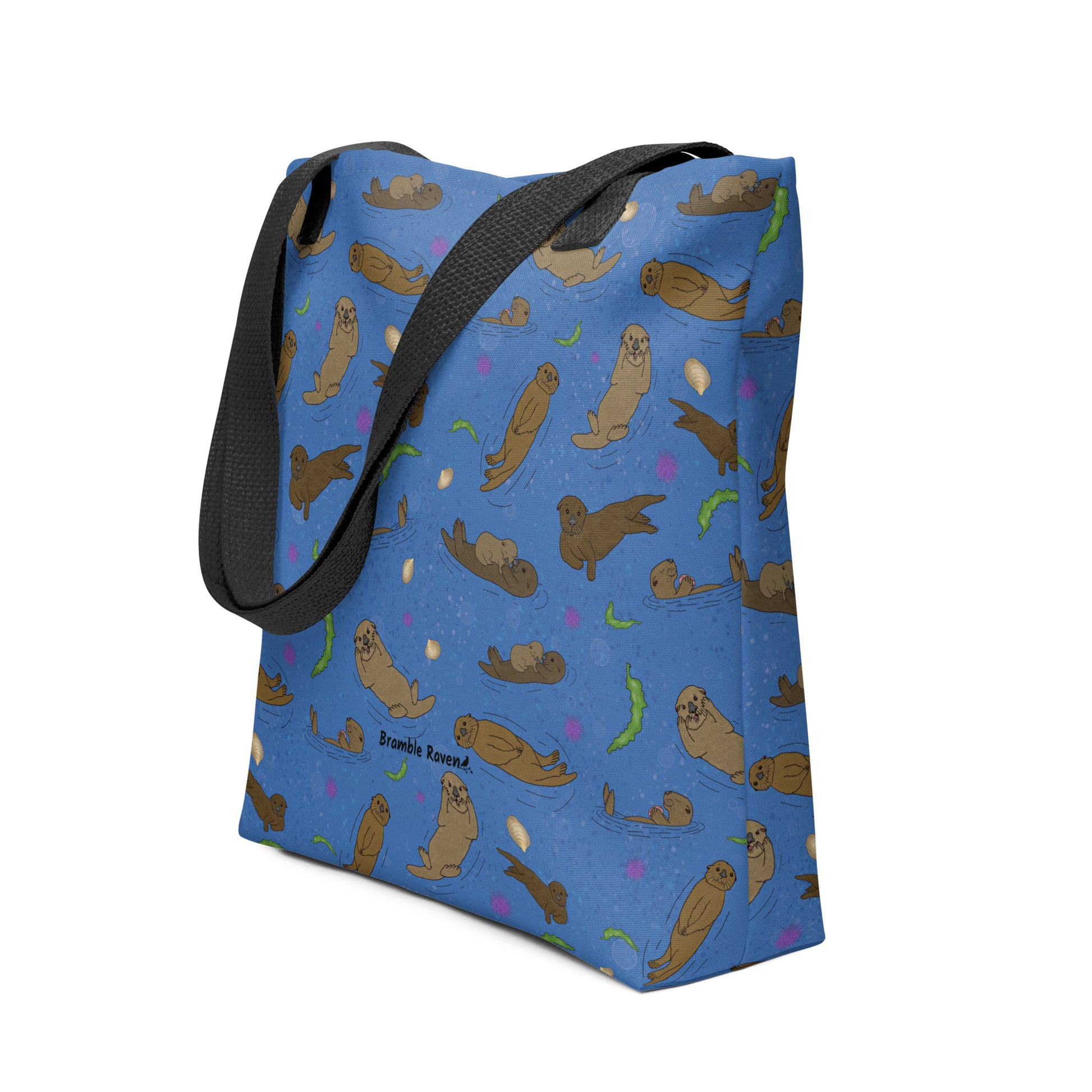 15 by 15 inch polyester tote bag with dual black cotton bull denim handles. It has a patterned design of sea otters, seashells, seaweed and sea urchins on a blue background. Shown standing upright with boxed corners.