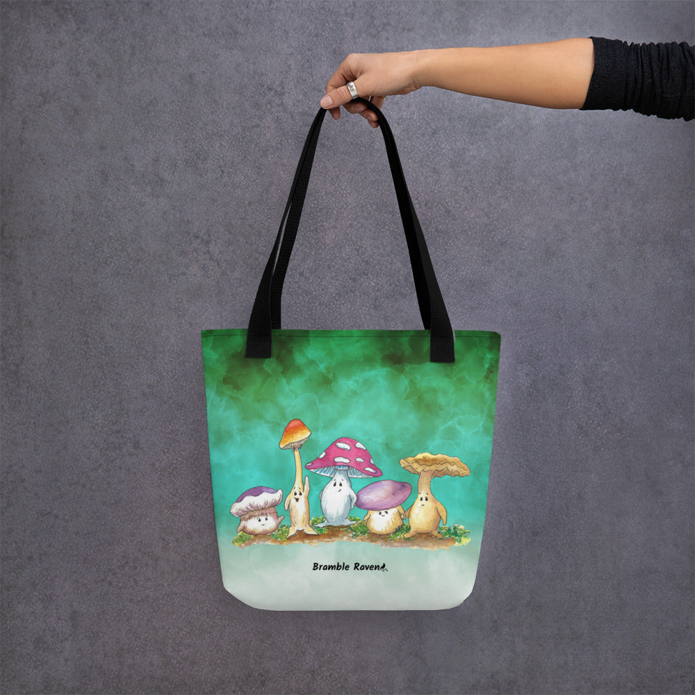 15 by 15 inch sturdy tote bag. Features Mushy and his whimsical mushroom friends on a green gradient background. Made of spun polyester with black cotton bull denim handles. Shown hanging from model's hand.