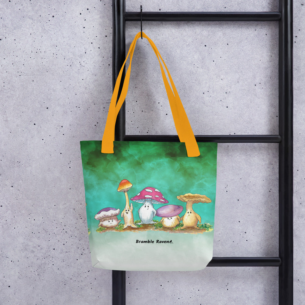 15 by 15 inch sturdy tote bag. Features Mushy and his whimsical mushroom friends on a green gradient background. Made of spun polyester with yellow cotton bull denim handles. Shown hanging from ladder.