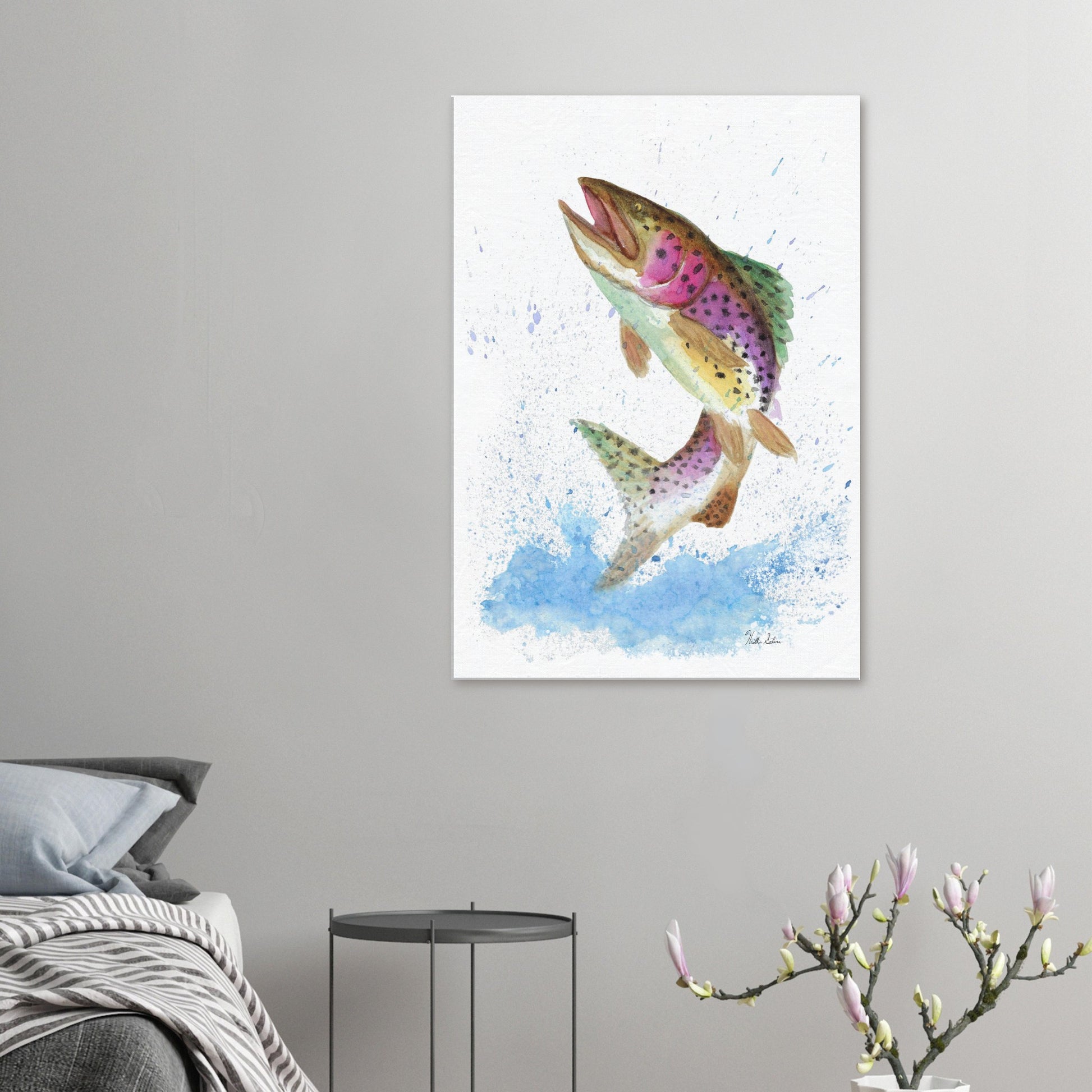 28 by 40 inch slim canvas wall art print featuring a watercolor painting of a rainbow trout leaping from the water. Shown on wall above grey bed, grey nightstand, and blooming branch decor.