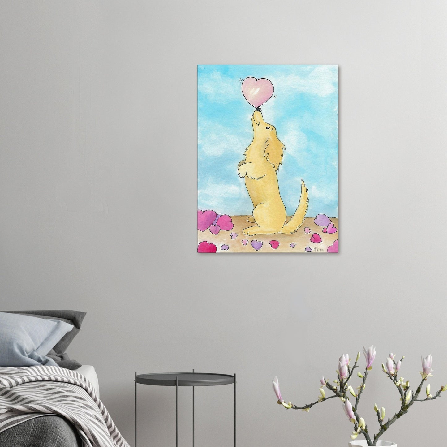 24 by 32 inch canvas wall art print of Heather Silver's watercolor painting, Puppy Love. It features a cute dog balancing a pink heart on its nose against a blue sky background. Canvas shown on wall above grey bed, grey nightstand, and blooming branch décor.