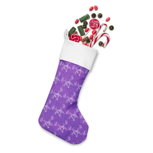 Limited Edition Purple Deer Skull Christmas Stocking.  7 by 18 inches. The front has a hand-illustrated deer skull design on a purple background with an off-white polyester fabric on the back. It has a white fold-over cuff and a loop for hanging. Shown stuffed with candy.