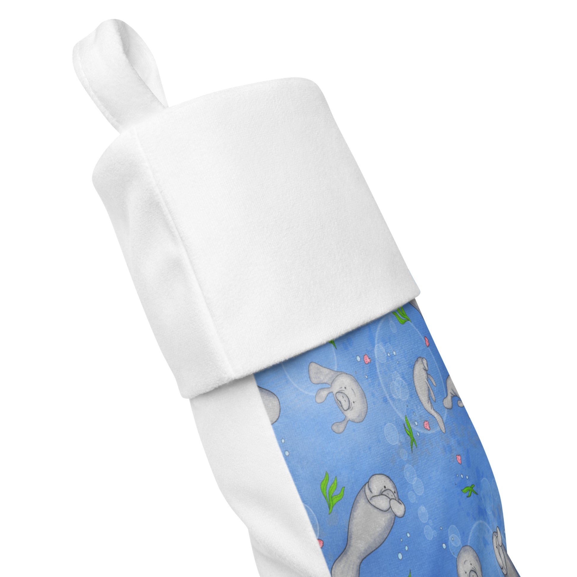 Limited Edition Manatee Christmas Stocking.  7 by 18 inches. The front has a hand-illustrated manatee design with an off-white polyester fabric on the back. It has a white fold-over cuff and a loop for hanging. Side view shows front and back fabric.