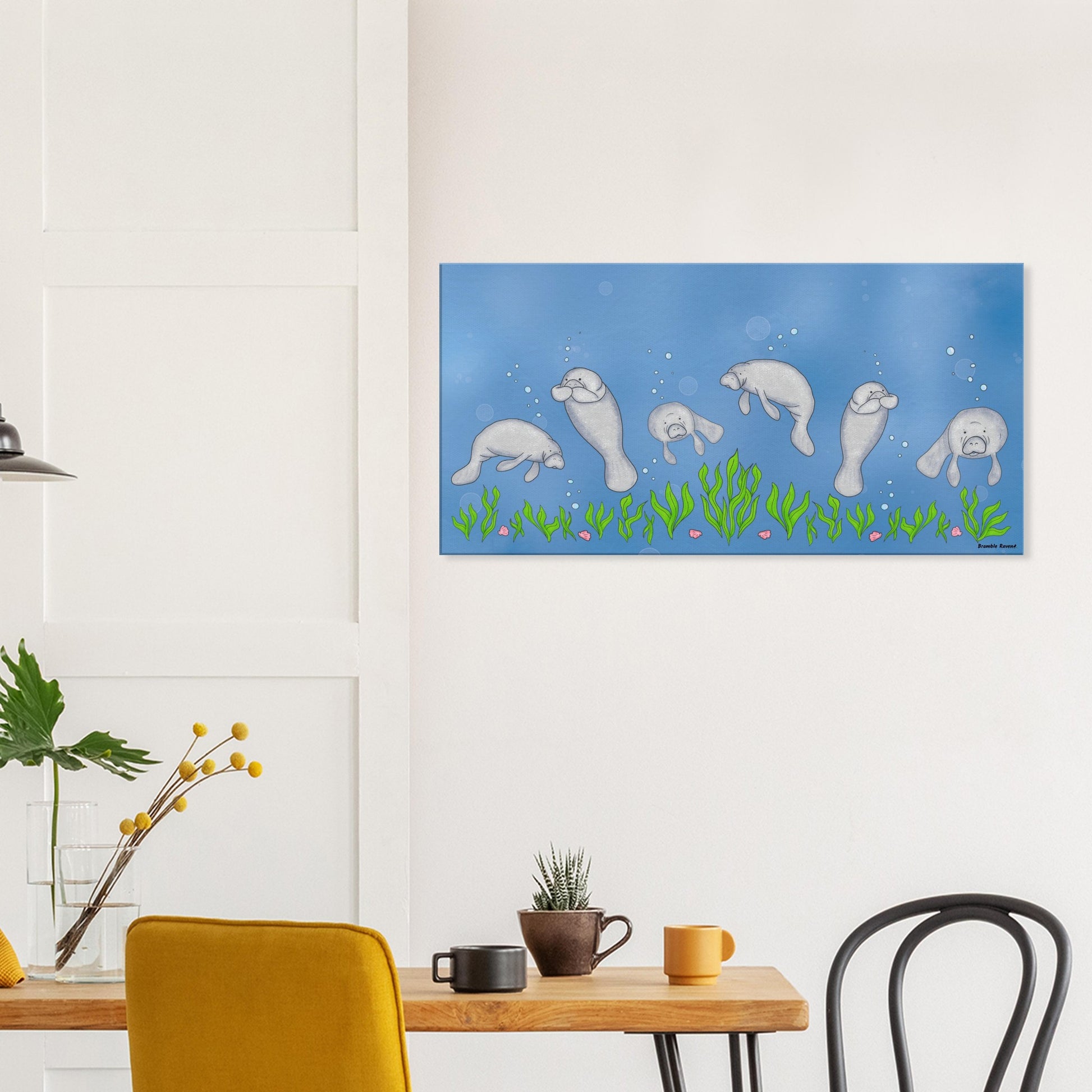 20 by 40 inch slim canvas wall art print featuring cute illustrated manatees swimming above the seabed. Shown on wall above wooden kitchen table with cups and chairs.