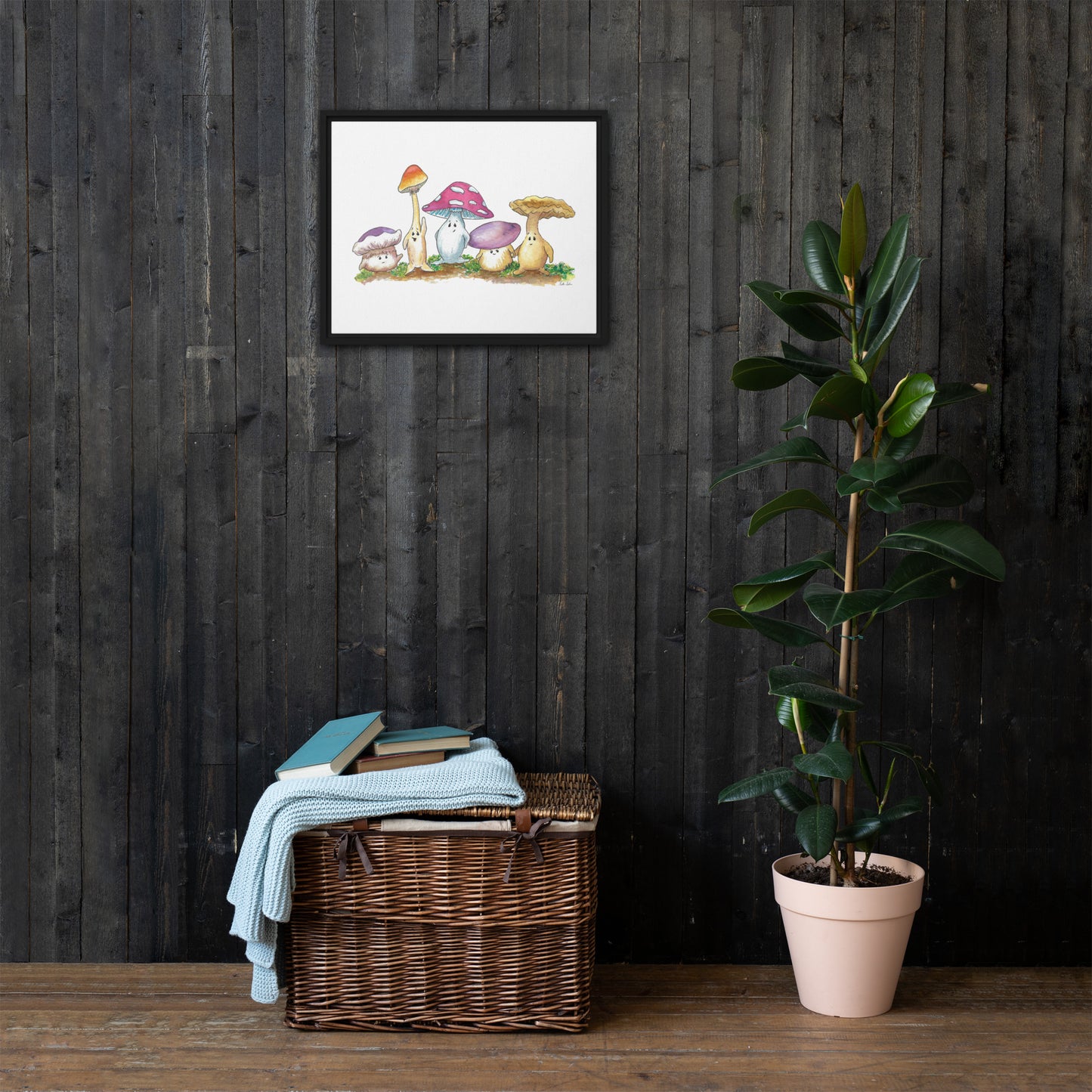 16 by 20 inch canvas print of Heather Silver's watercolor painting, Mushy and Friends. Framed in a black pine wood frame that gives it a floating canvas effect. Shown on wood wall above wicker basket and potted plant.