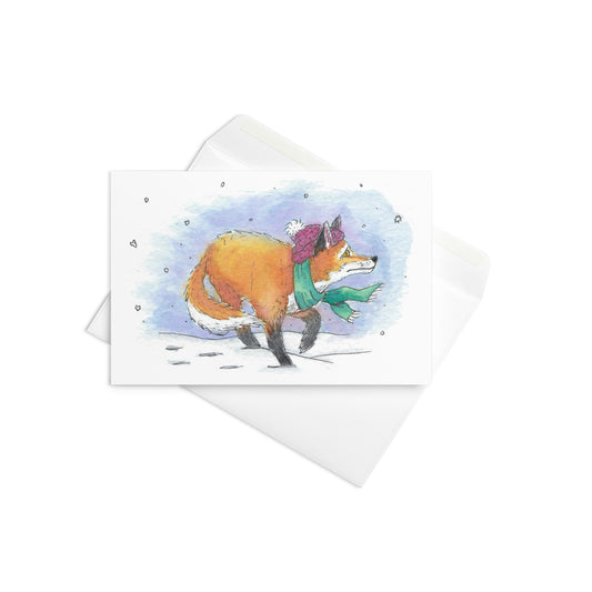 4 by 6 inch greeting card with envelope. Front has winter fox watercolor illustration with his hat and scarf in the snow. Inside is blank.