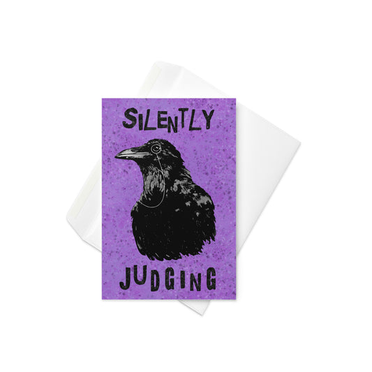4 by 6 inch greeting card. Features our monocle-wearing Silently Judging Crow design with purple paint splatter background. Inside is blank. Comes with white envelope.