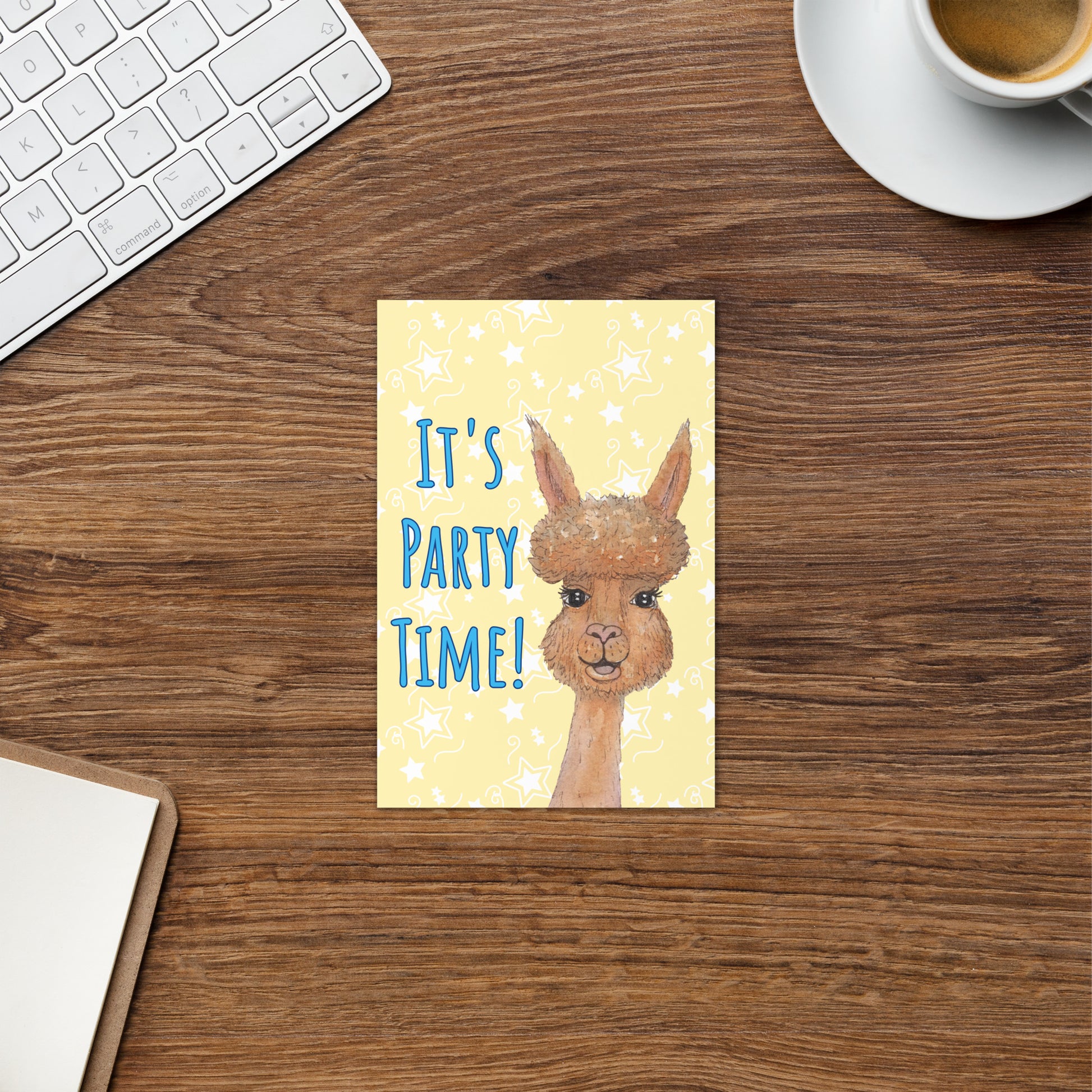 4 by 6 inch party alpaca greeting card. Image shows front cover by keyboard and coffee cup. Background is pastel yellow with white star accents. Front has watercolor alpaca and text: It's party time!