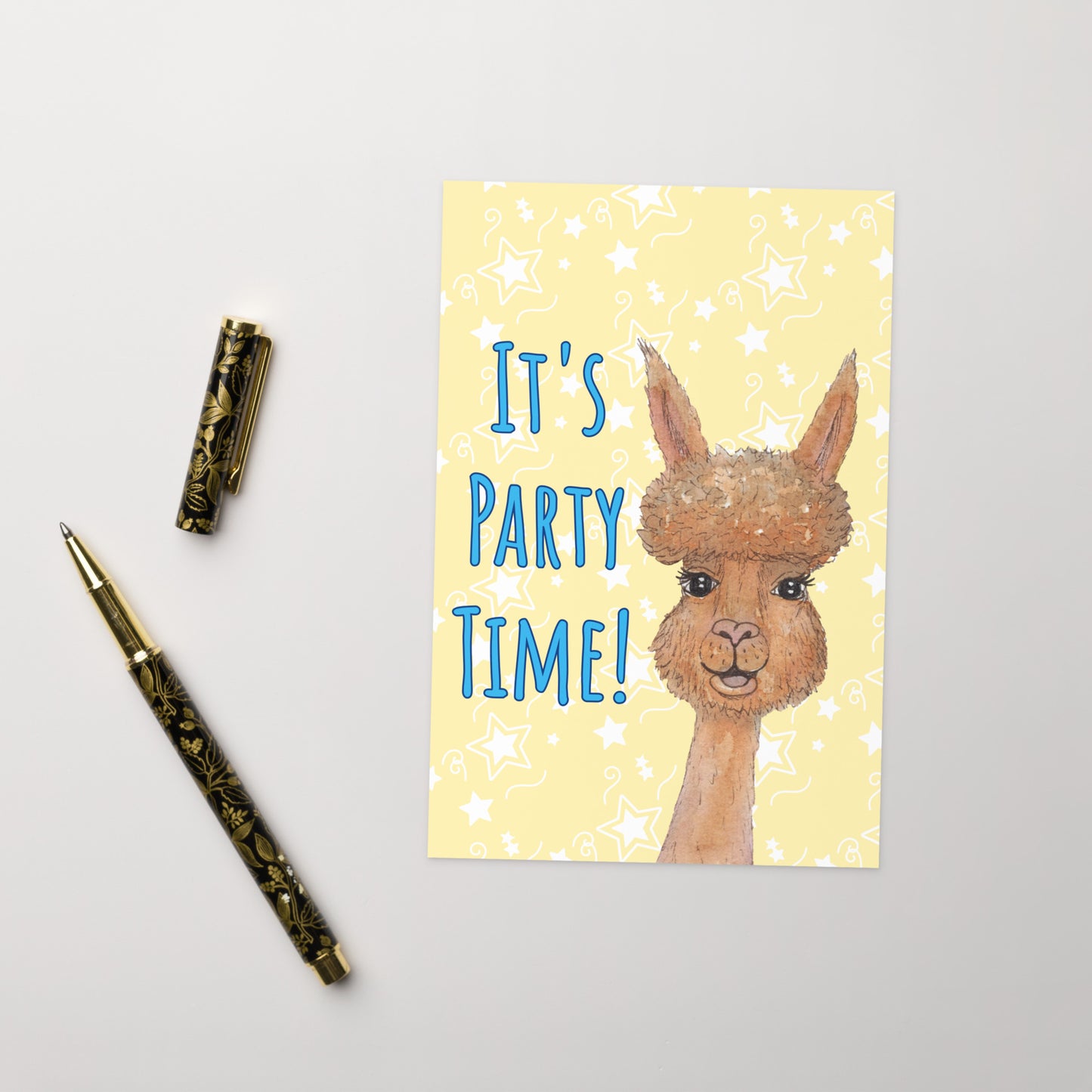 4 by 6 inch party alpaca greeting card and envelope. Image shows cover  by ballpoint pen. Background is pastel yellow with white star accents. Front has watercolor alpaca and text: It's party time!