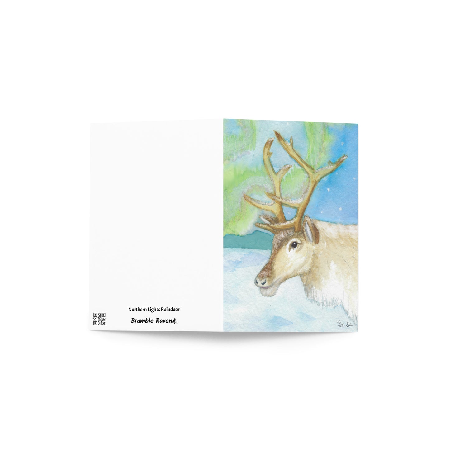 4 x 6 inch greeting card. Features watercolor print of a reindeer in the snow with northern lights in the sky. Blank inside. Comes with a white envelope. Shows front and back cover.