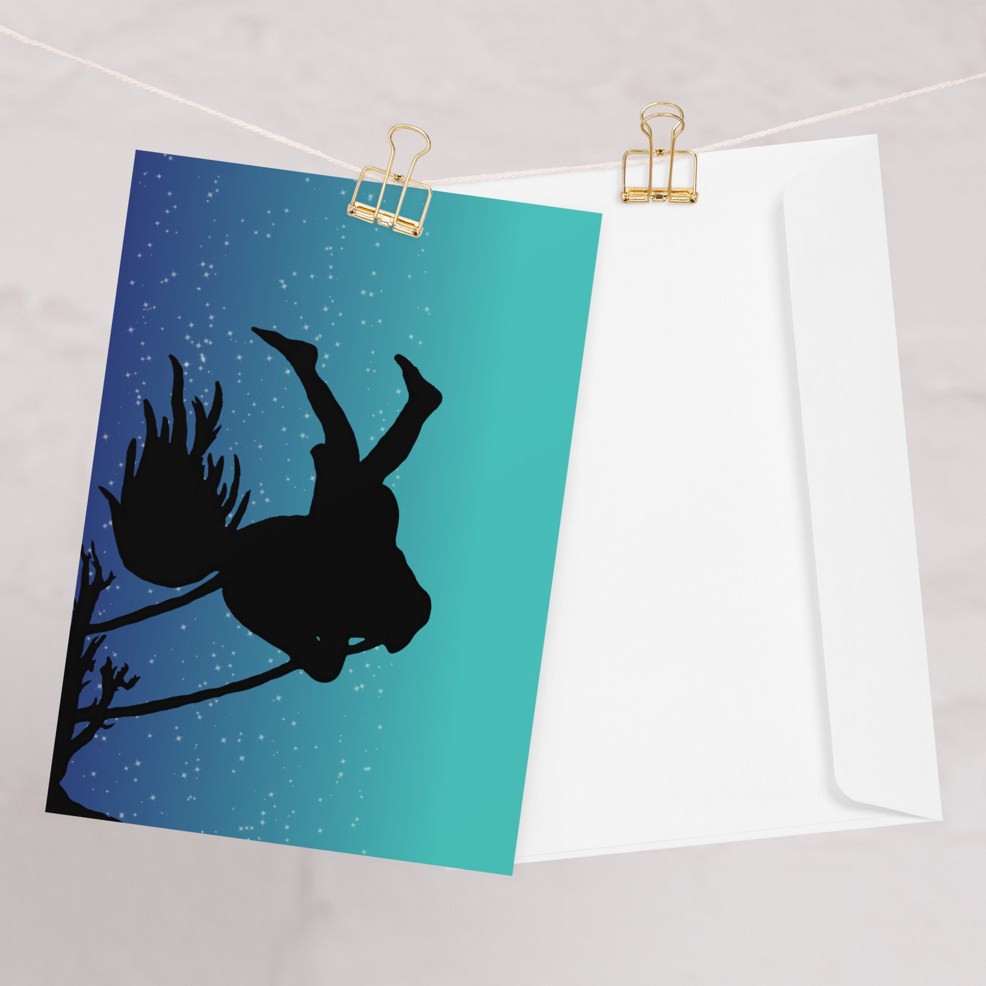 Pack of ten 5.5 by 8.5 inch Night Swing greeting cards and envelopes. Front shows silhouette of a girl in a tree swing against a starry summer night sky. Inside is blank.  One card shown on clothesline with white envelope.