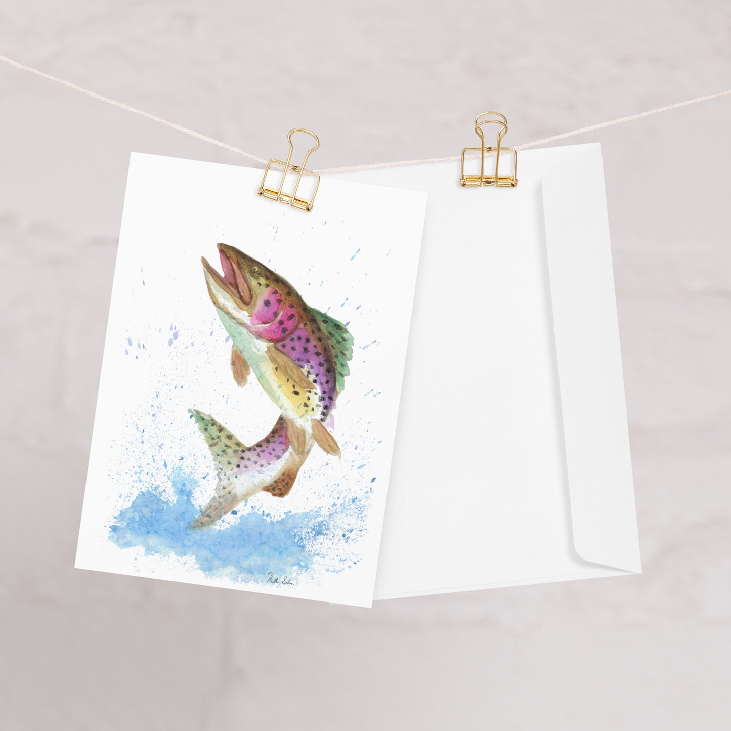Ten greeting cards with print of watercolor rainbow trout on the front. Inside is blank. Comes with envelopes. Cards measure 5.5 by 8.5 inches. Made with 350 gsm 150lb coated paperboard with vibrant printing. One card shown on clothesline with white envelope.