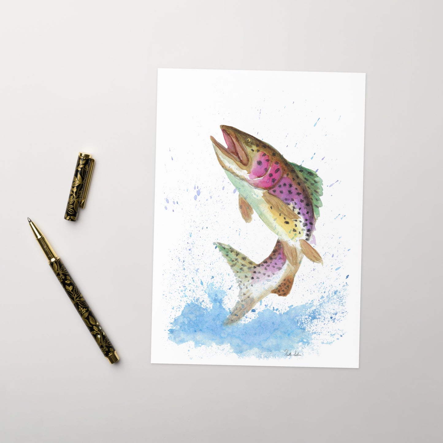 Ten greeting cards with print of watercolor rainbow trout on the front. Inside is blank. Comes with envelopes. Cards measure 5.5 by 8.5 inches. Made with 350 gsm 150lb coated paperboard with vibrant printing. Shown on tabletop by ballpoint pen.
