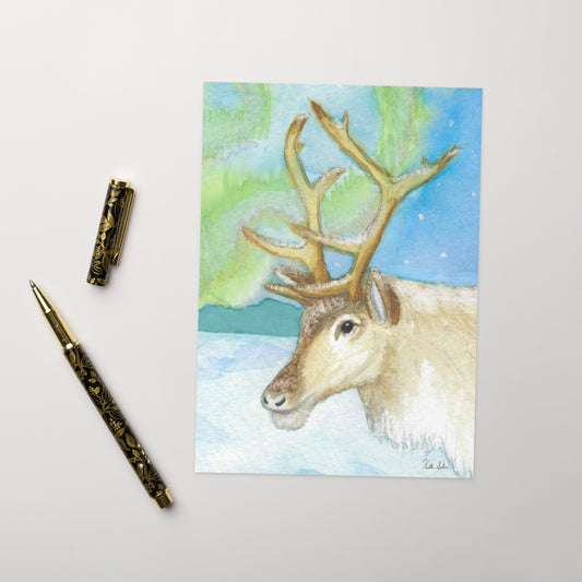 Ten beautiful coated greeting cards with print of watercolor reindeer viewing the northern lights on the front. Inside is blank. Comes with ten envelopes. Cards measure 5 by 7 inches. Shown on tabletop by ballpoint pen.