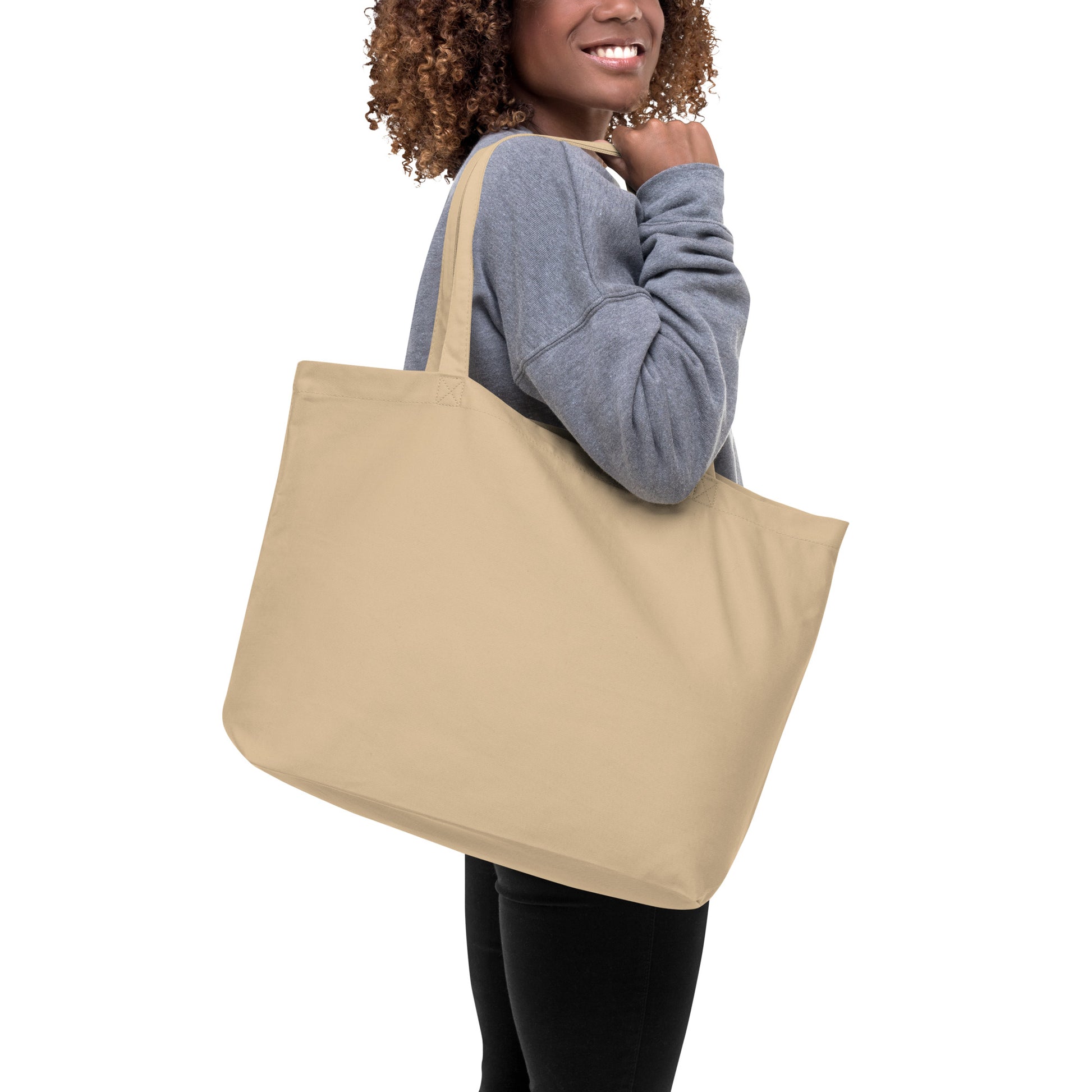 Large tan organic cotton tote bag. Has a watercolor mother hand and chicks print. Holds up to 30 pounds. Shown on model's shoulder.