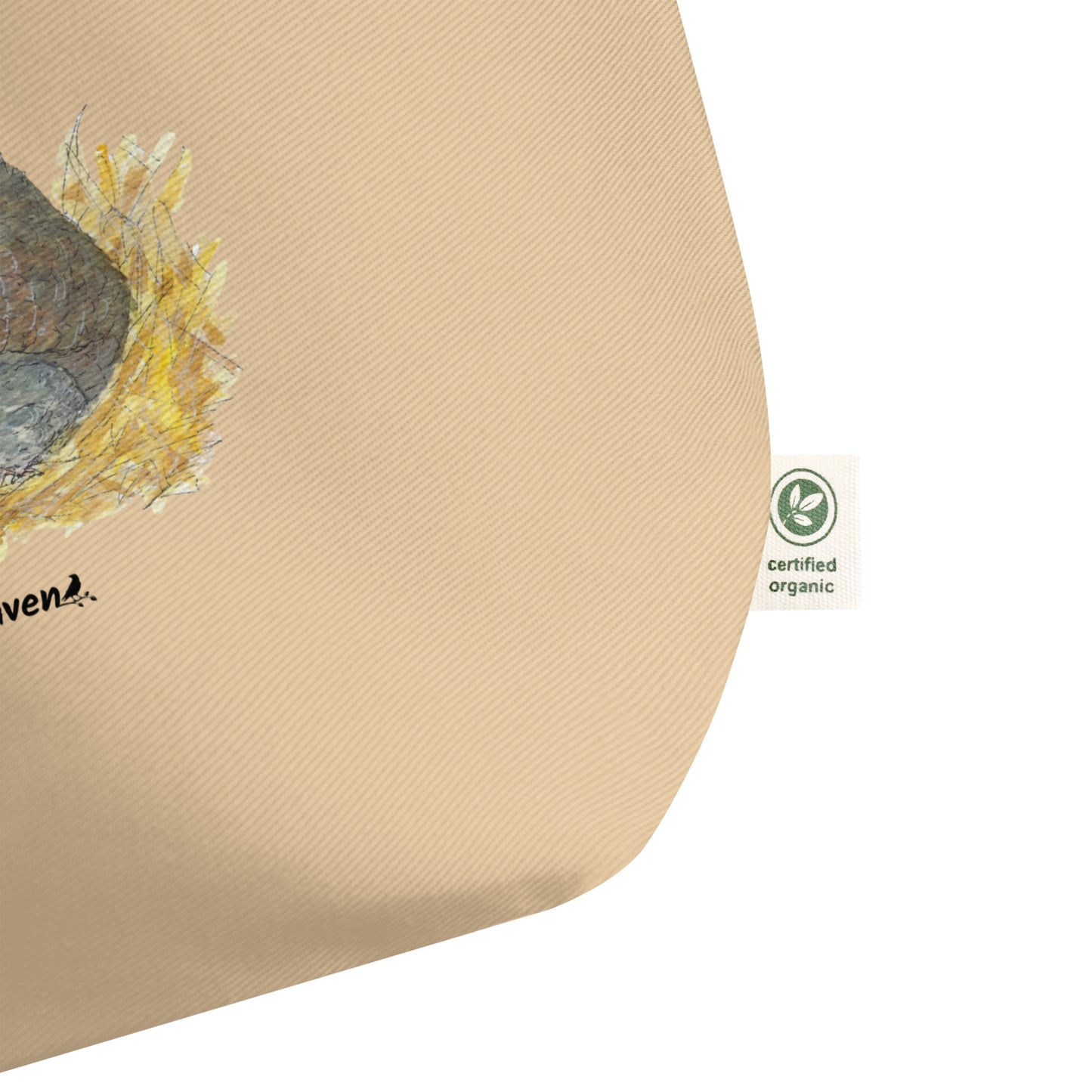 Large tan organic cotton tote bag. Has a watercolor mother hand and chicks print. Detail view of certified organic tag.