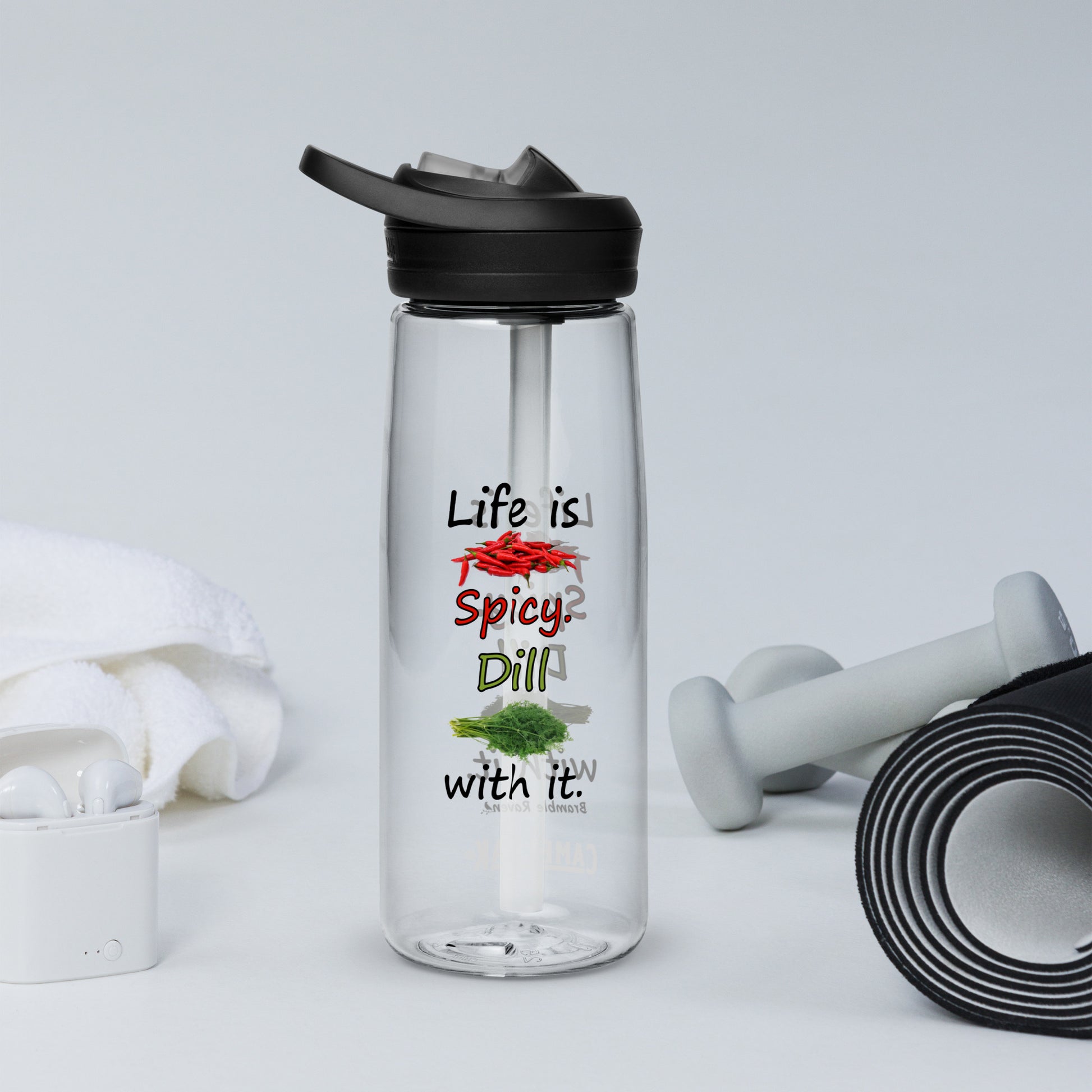 25 ounce sports water bottle with spill-proof lid and bite valve. Clear stain and odor-resistant BPA-free plastic. Features double-sided design of "Life is spicy. Dill with it" phrase with peppers and dill weed images. Shown by yoga mat, weights, and towel.
