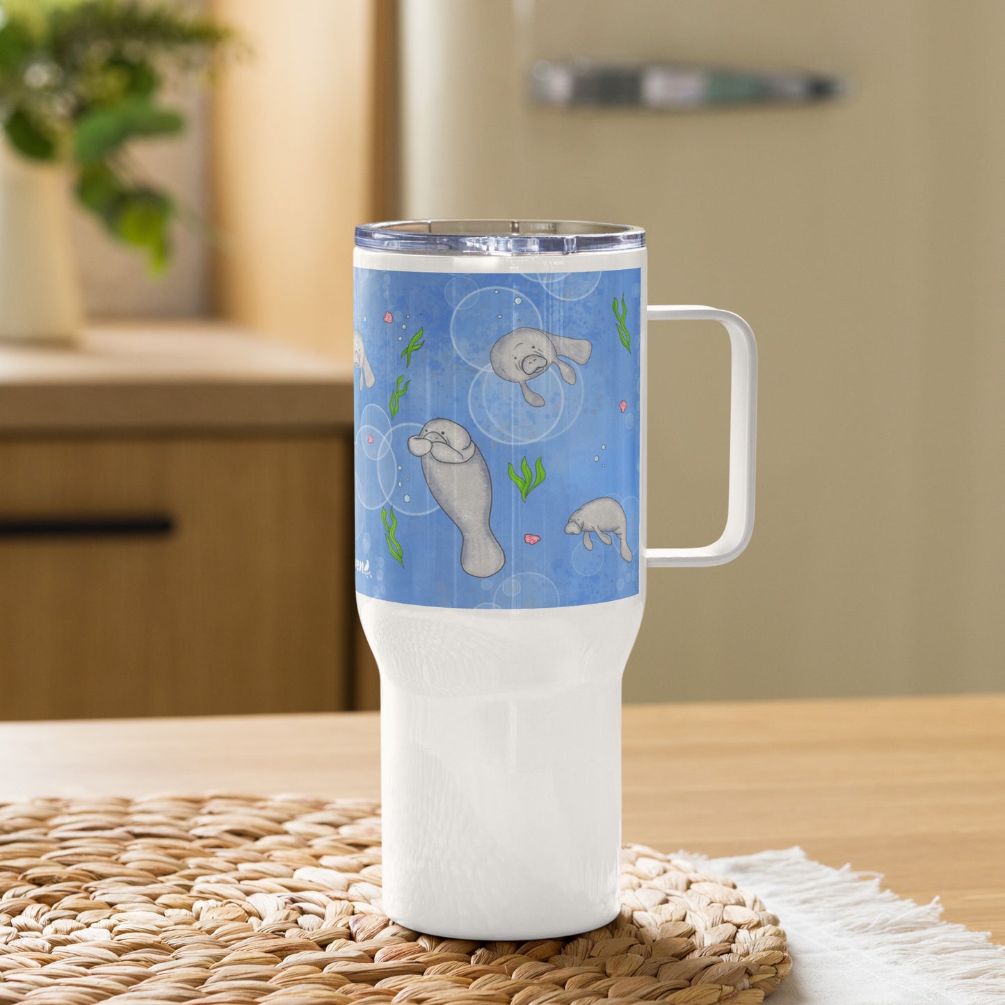 Stainless steel travel mug with handle. Holds 25 ounces of hot or cold drinks. Has wraparound illustrated manatees design. Fits most car cup holders. Comes with spill-proof BPA-free plastic lid. Mug shown on tabletop.