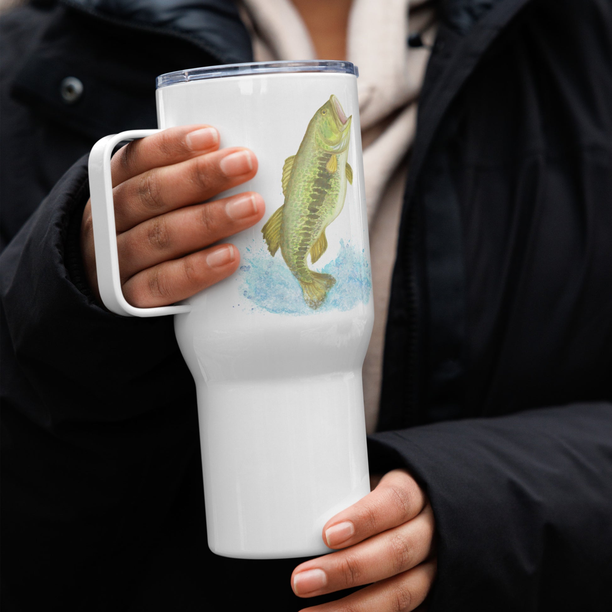 Stainless steel travel mug with handle. Holds 25 ounces of hot or cold drinks. Has print of watercolor bass fish on both sides. Fits most car cup holders. Comes with spill-proof BPA-free plastic lid. Mug shown on model's hands.