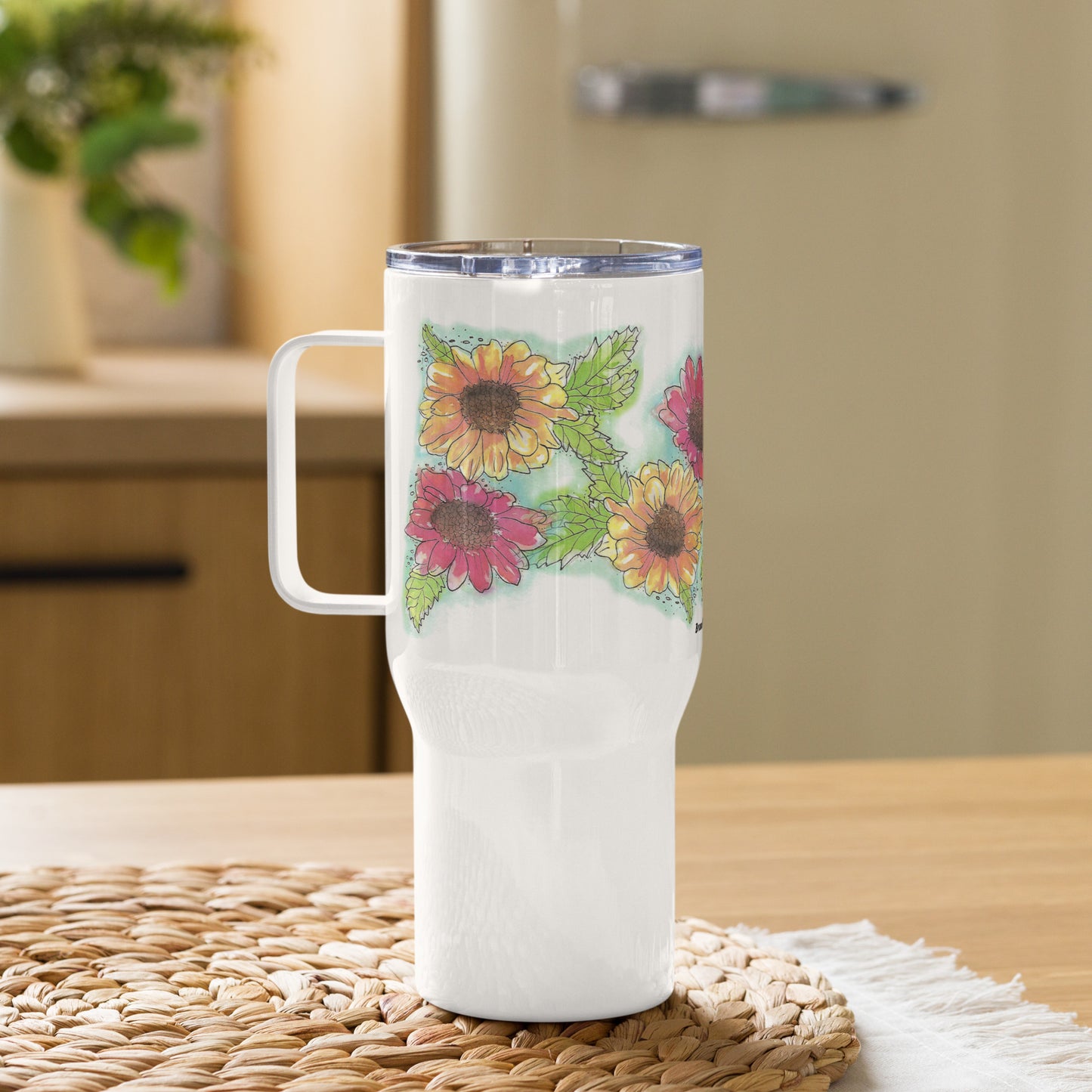 Gerber daisies stainless steel travel mug with handle. Holds 25 ounces and has a BPA-free plastic lid. Shown on woven placemat.