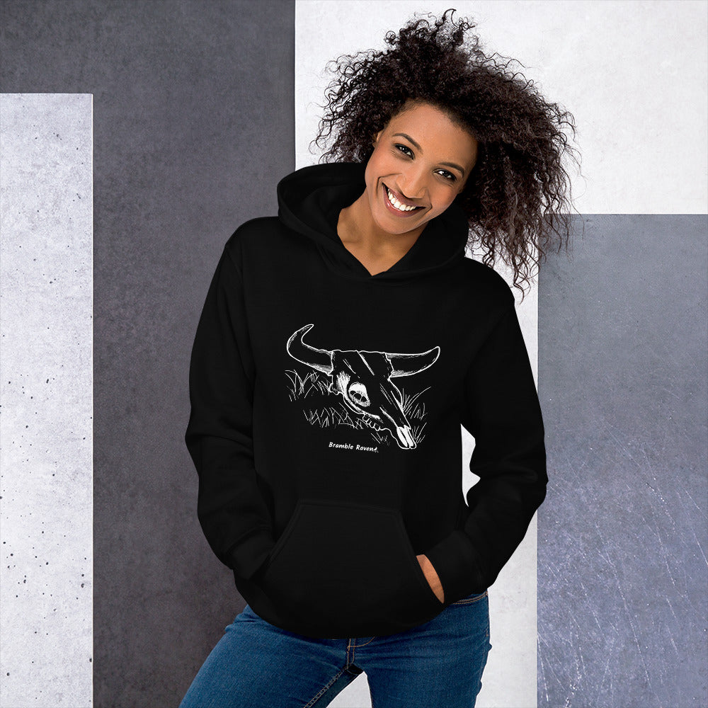 Black colored unisex hoodie. Front has image of a cow skull cradling a bird nest. Features double-lined hood and front pouch pocket. Shown on female model.
