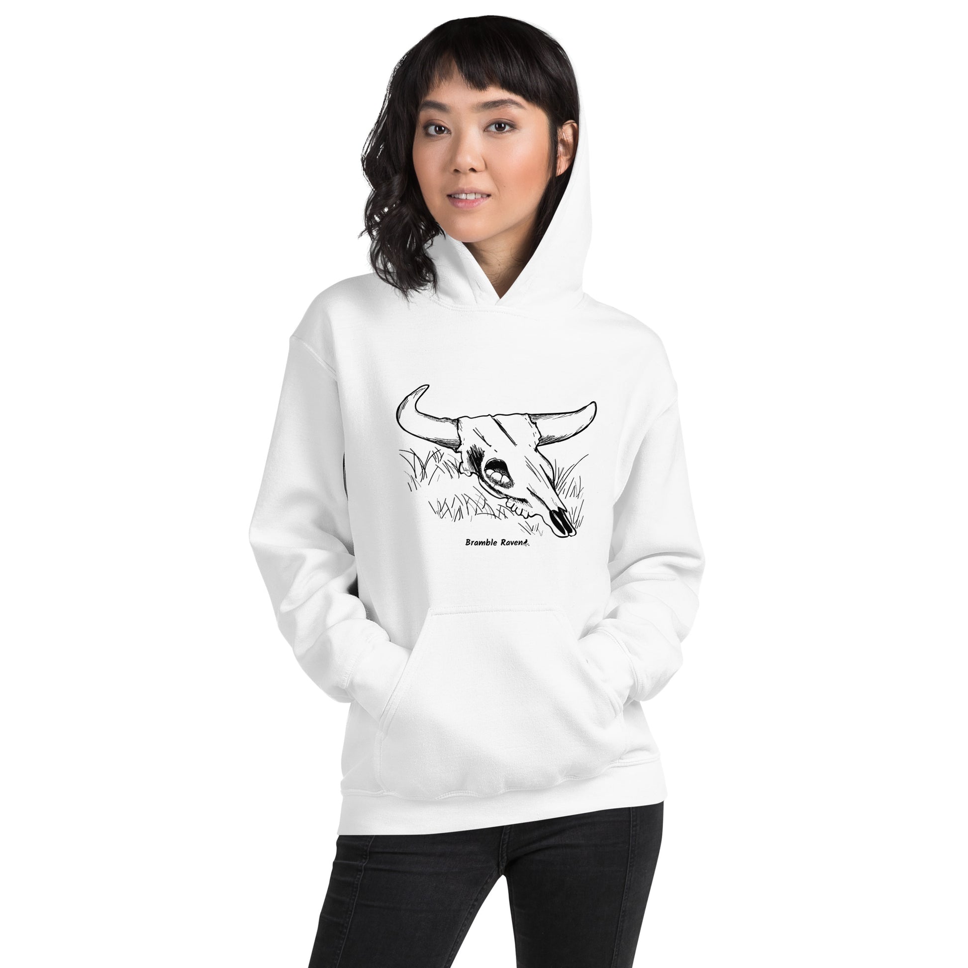 White colored unisex hoodie. Front has image of a cow skull cradling a bird nest. Features double-lined hood and front pouch pocket. Shown on female model.