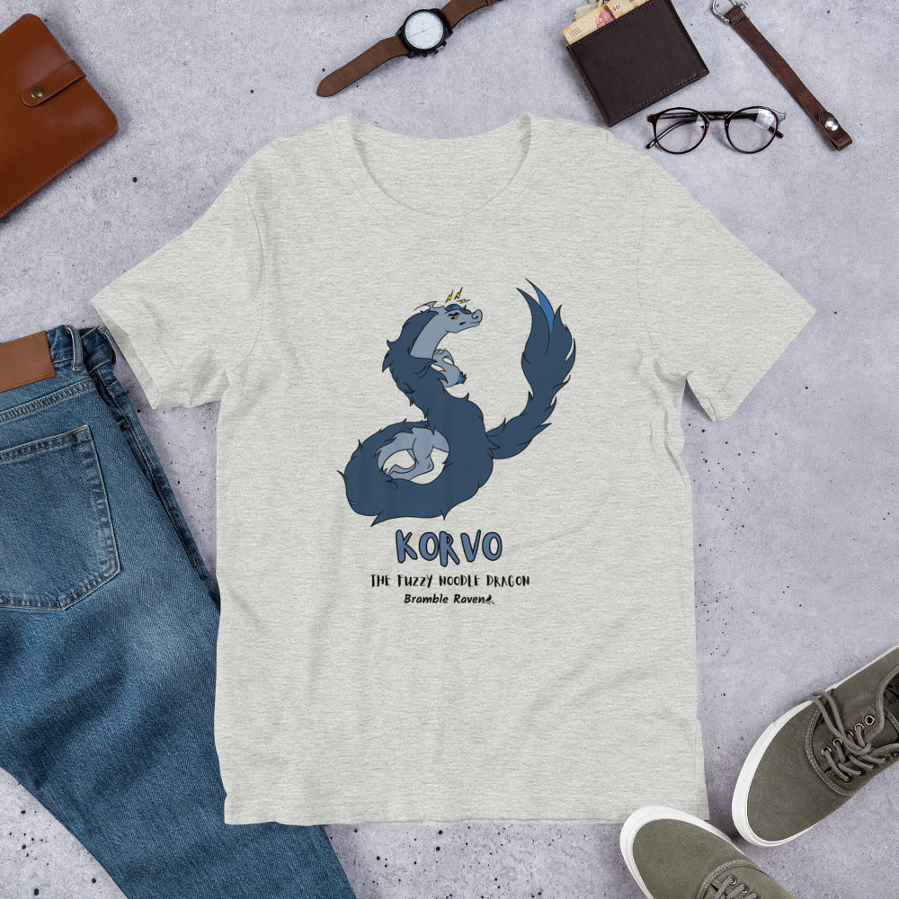 Korvo the angry Fuzzy Noodle Dragon on an athletic heather grey unisex t-shirt. Shown surrounded by pants, shoes, glasses, a watch, and wallet.