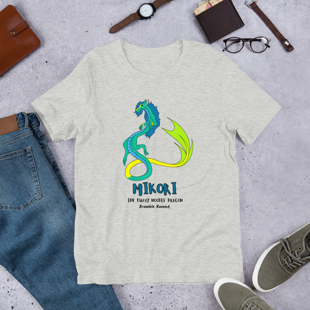 Mikori the Fuzzy Noodle Dragon on an athletic heather grey unisex t-shirt. Shown surrounded by pants, shoes, glasses, a watch, and wallet.