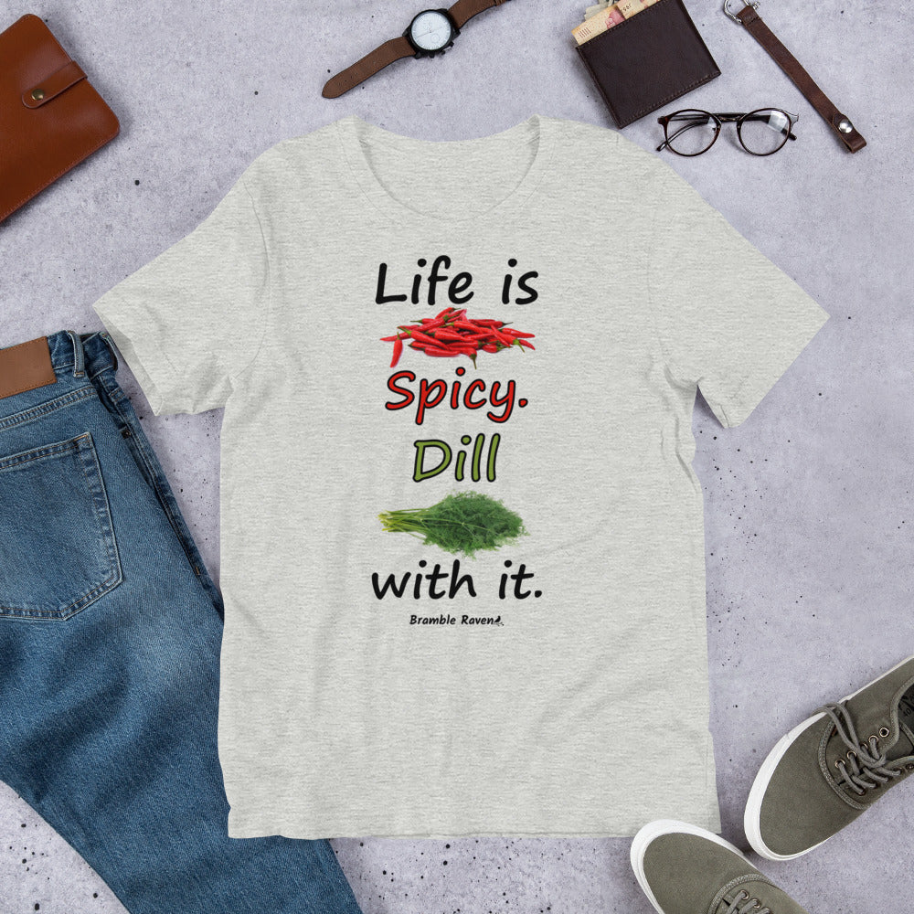 Athletic heather grey colored unisex t-shirt. Features text: Life is Spicy. Dill with it. Graphic of chili peppers and dill weed. Made of preshrunk cotton with side seams. Shown on floor by pants, shoes, wallet and glasses.