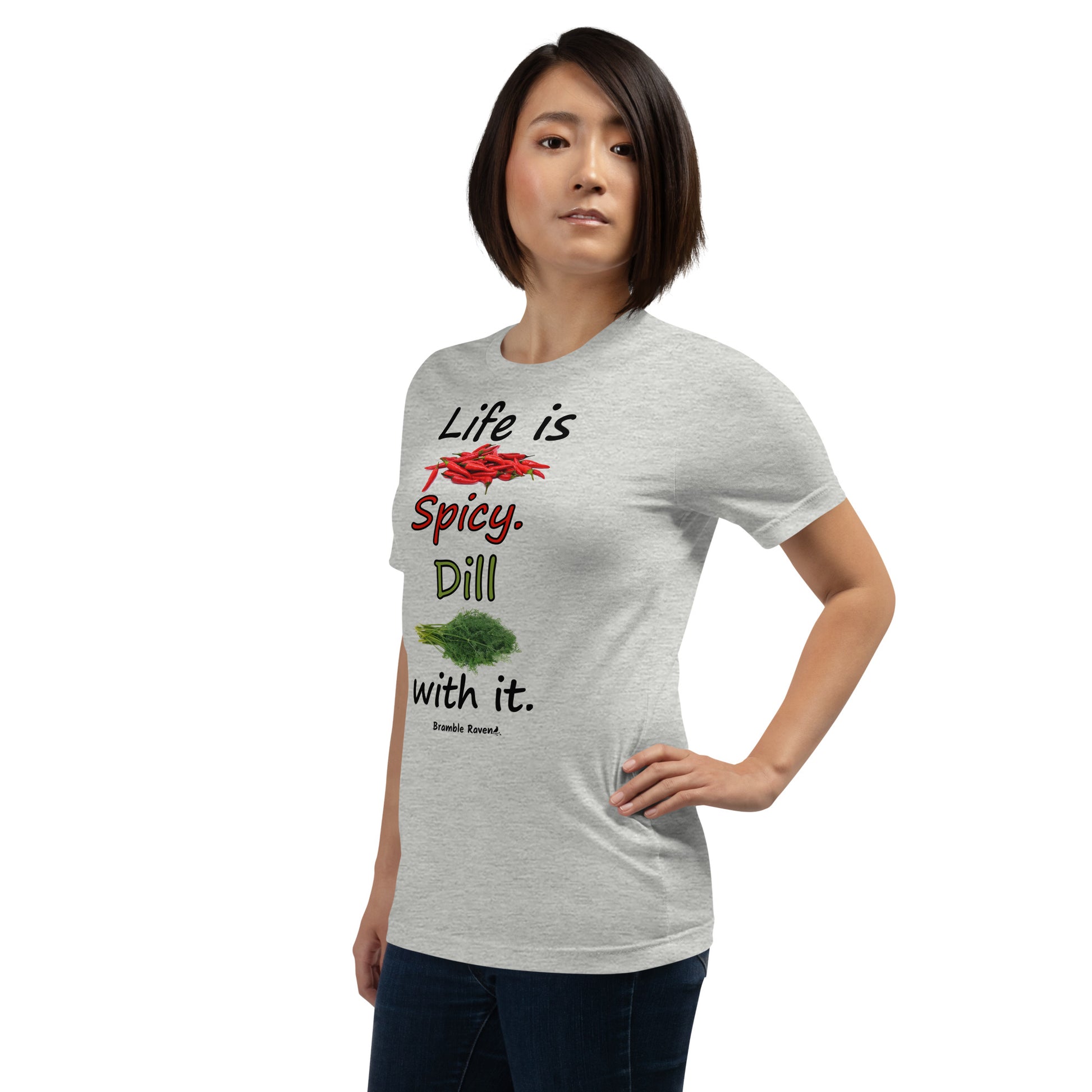 Athletic heather grey colored unisex t-shirt. Features text: Life is Spicy. Dill with it. Graphic of chili peppers and dill weed. Made of preshrunk cotton with side seams. Shown on female model facing left.